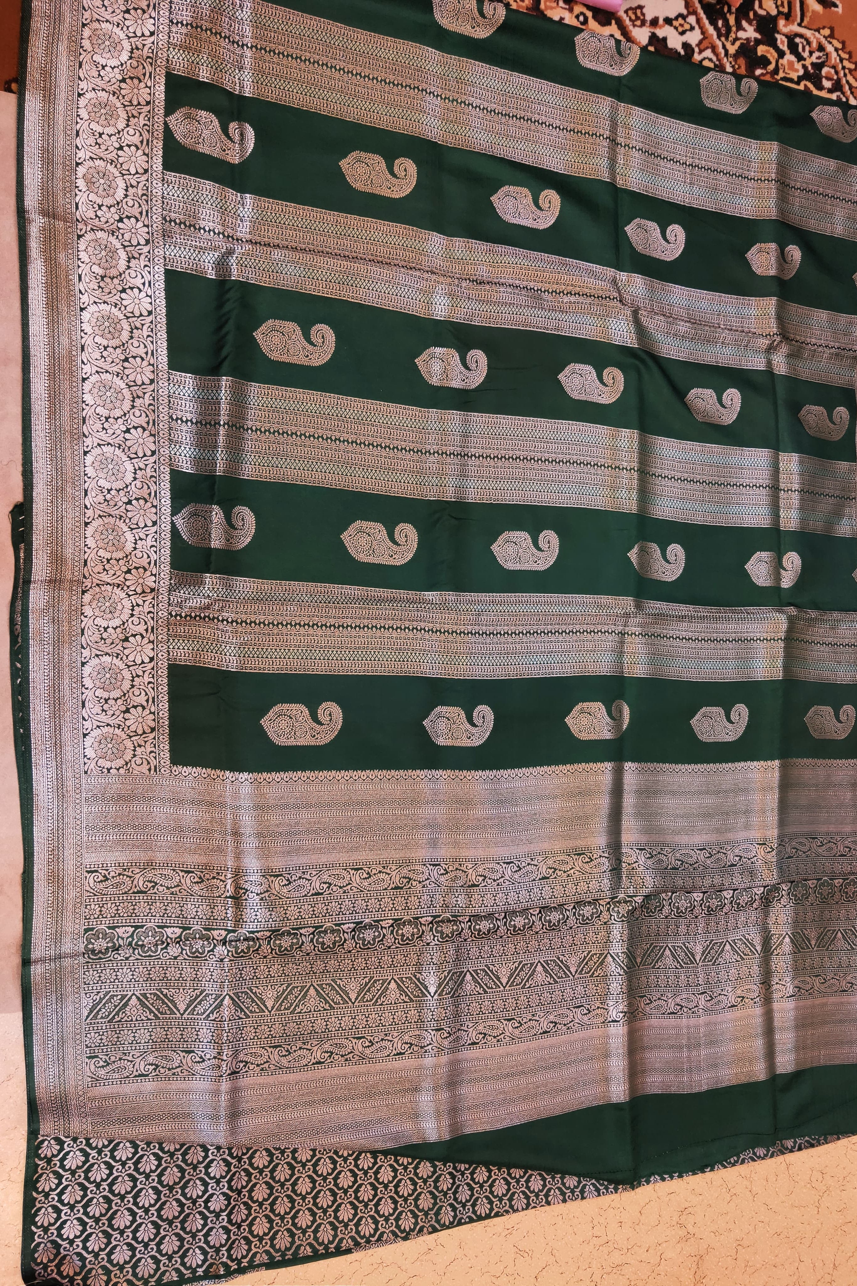 Green and beige saree with intricate patterns on a plain background