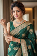 Woman wearing a green saree with gold patterns indoors