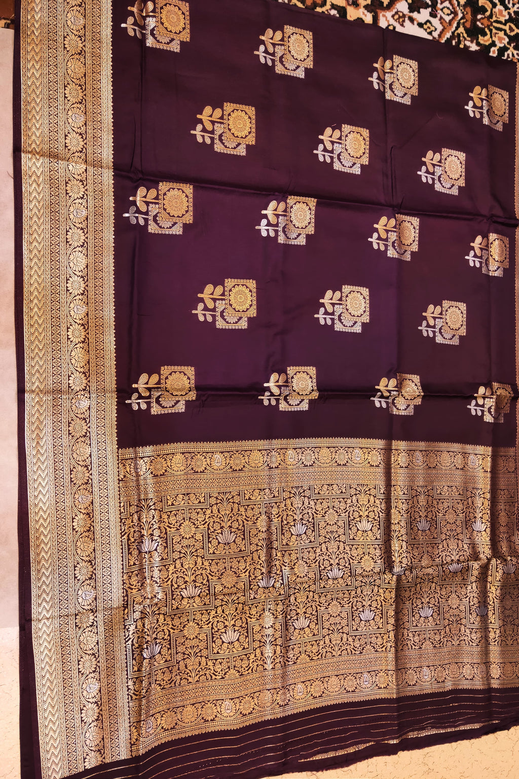 Decorative purple fabric with gold and white patterns on a plain background
