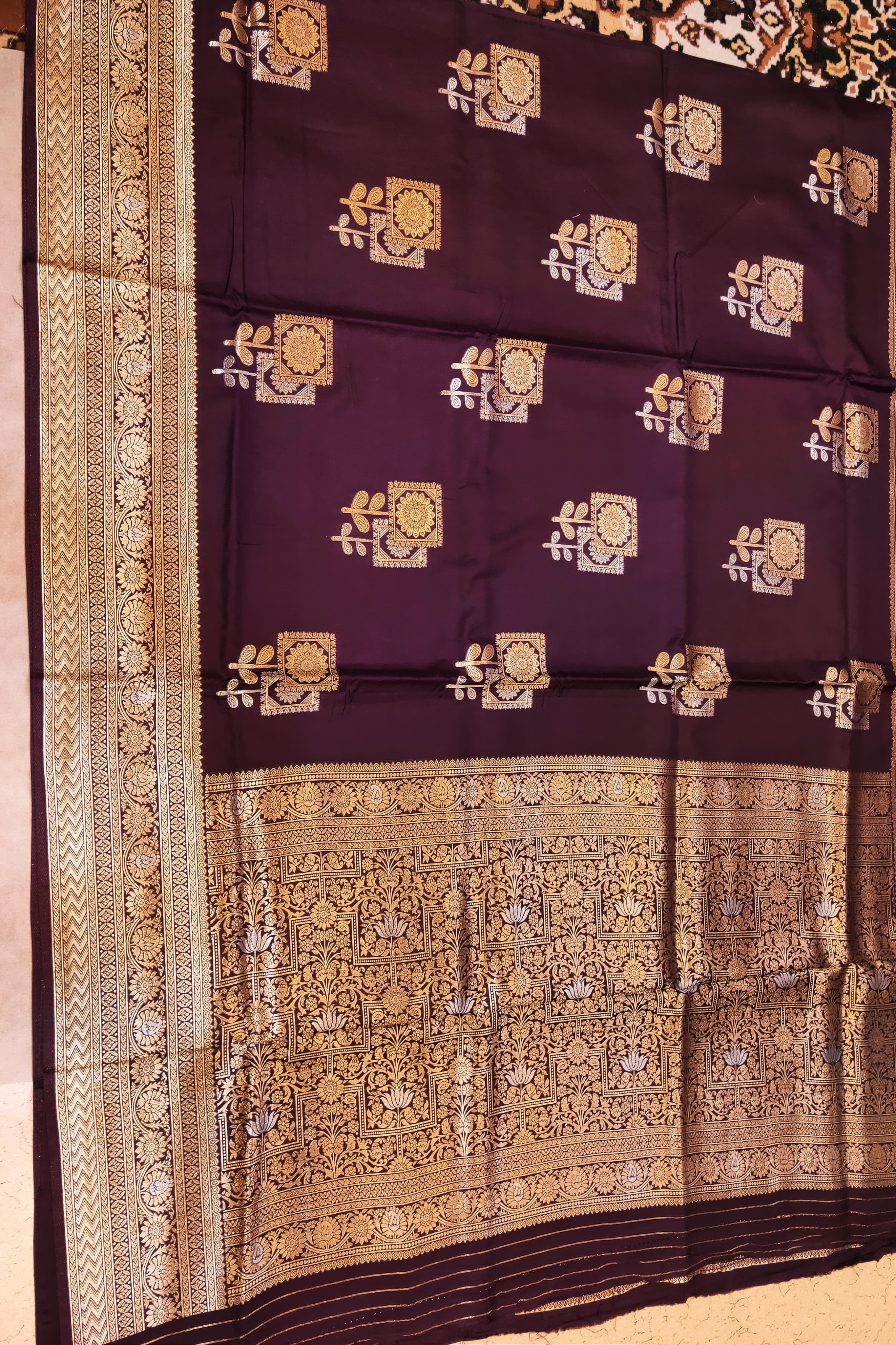 Decorative purple fabric with gold and white patterns on a plain background