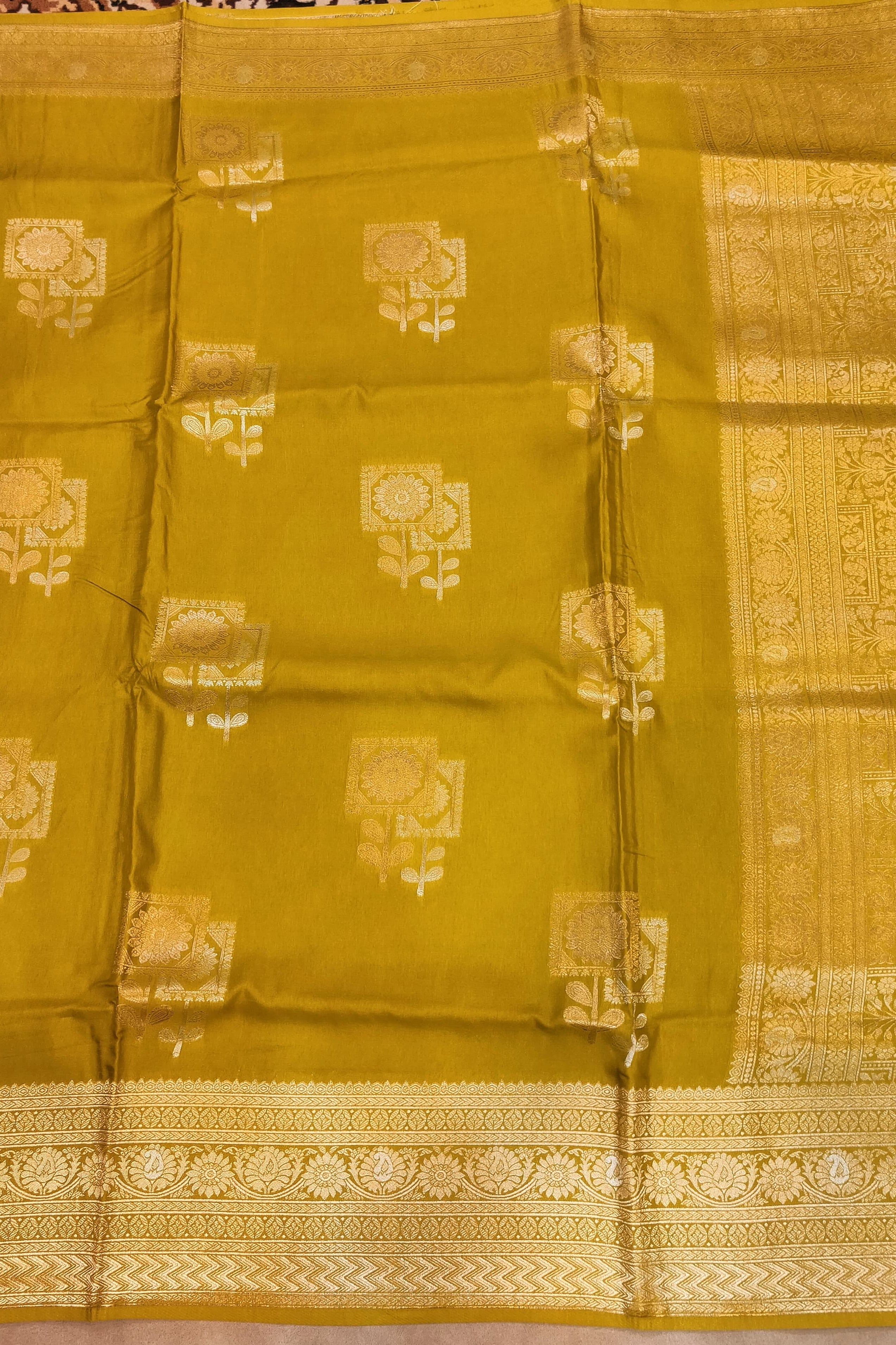 Yellow saree with gold patterns on a plain background