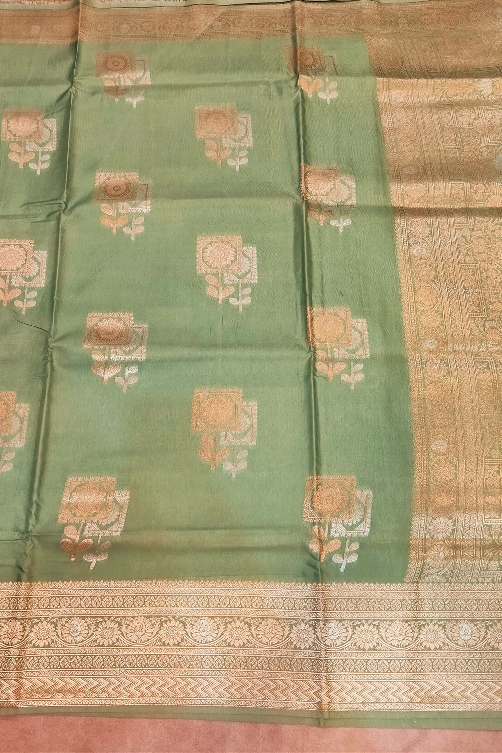 Green saree with gold patterns on a pink background