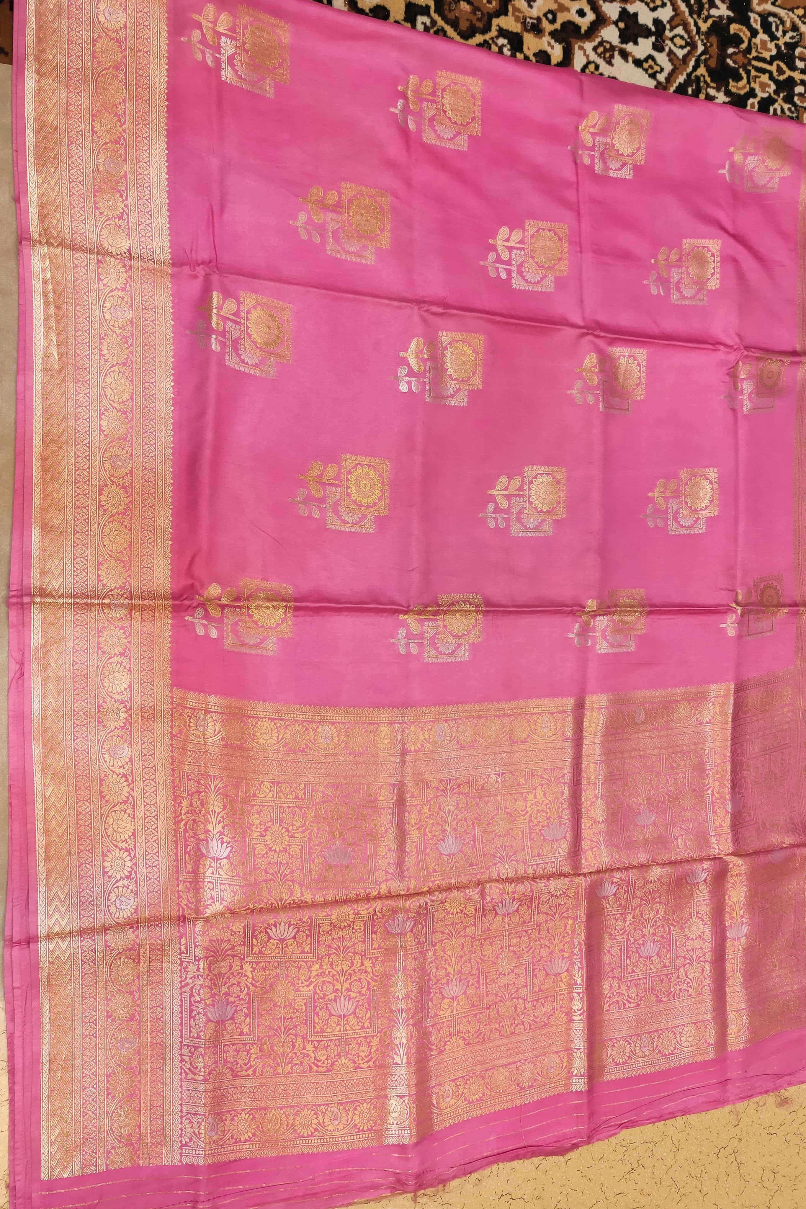 Pink saree with gold patterns on a plain background