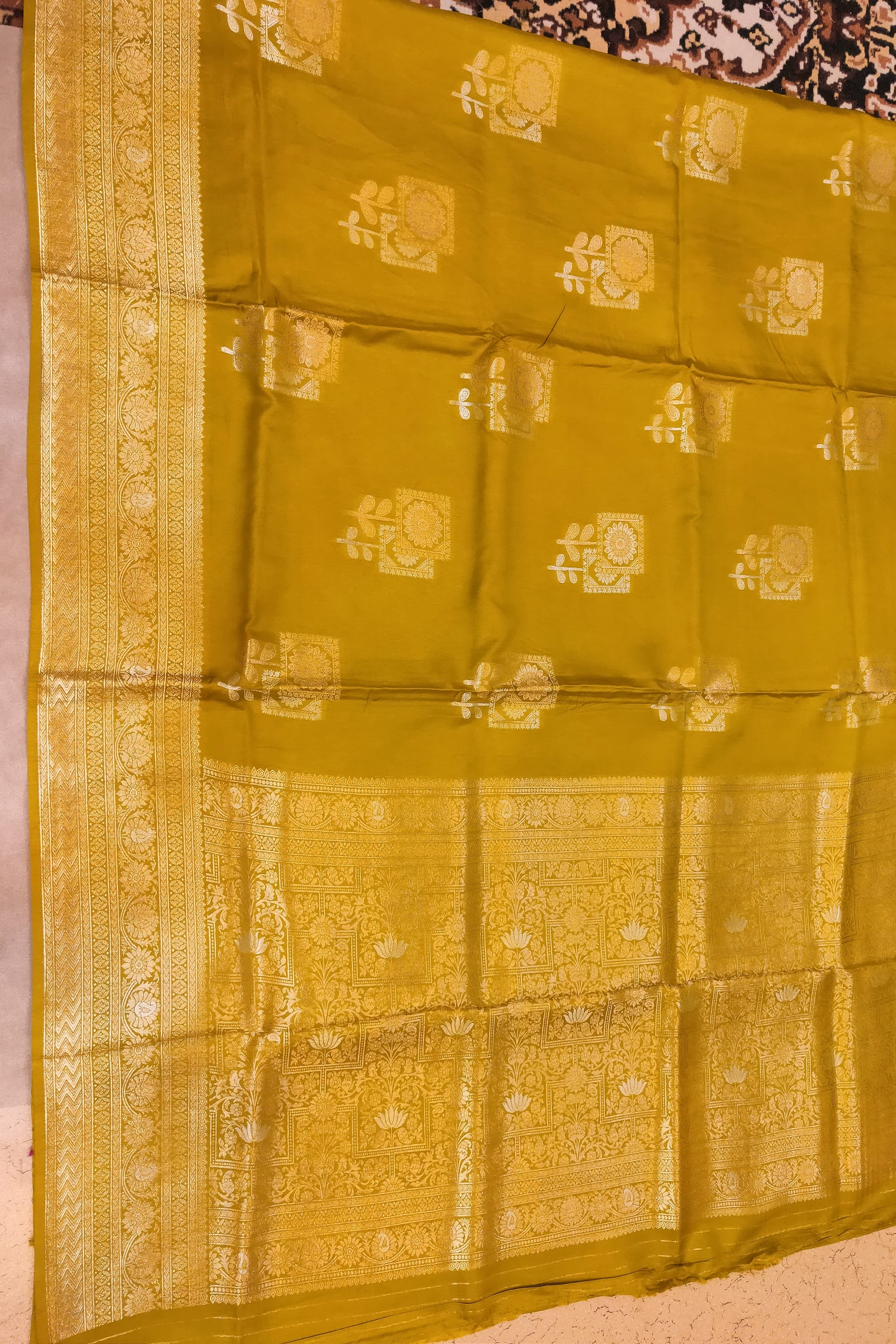 Yellow saree with gold patterns on a plain background