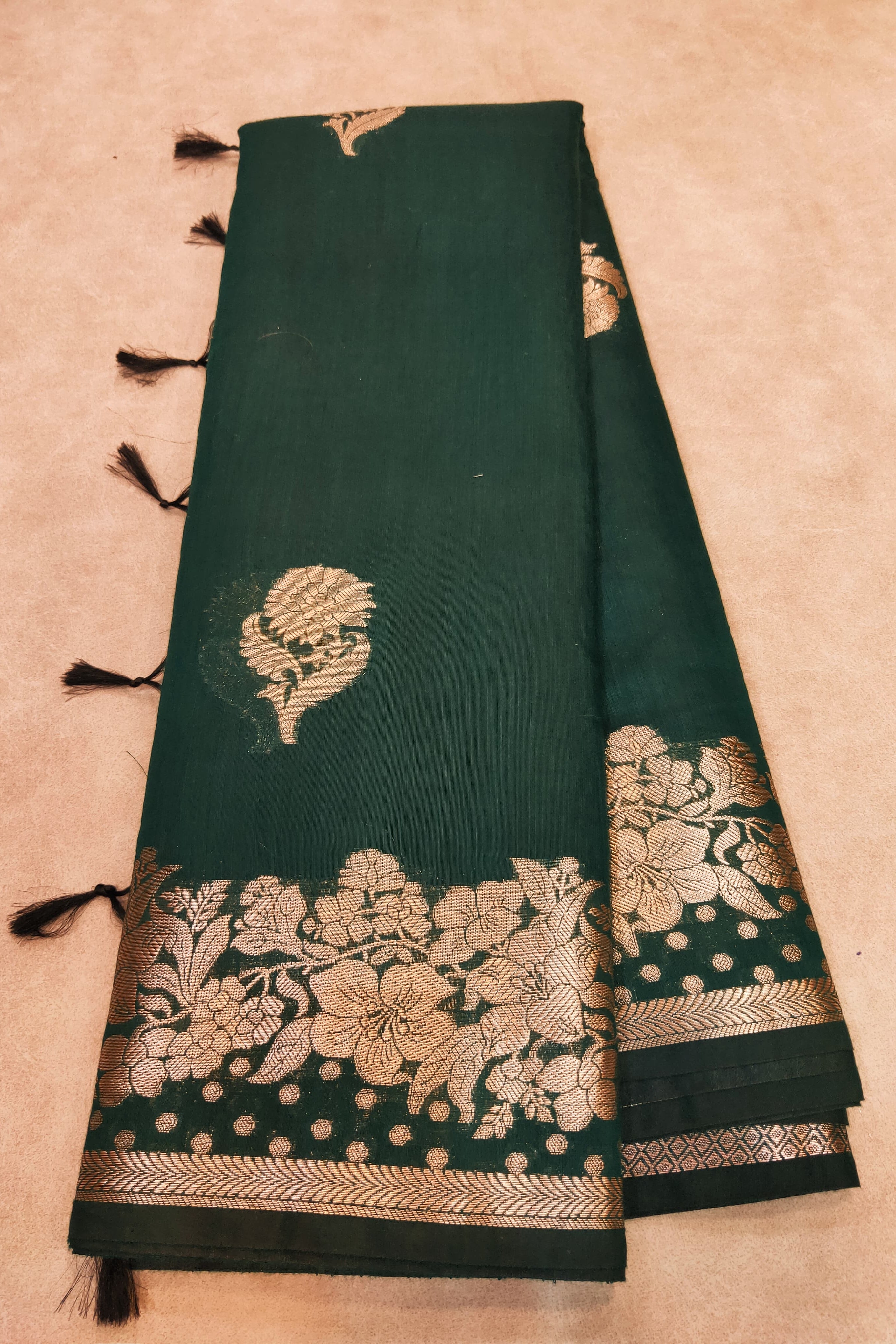 Green saree with gold floral patterns on a beige background
