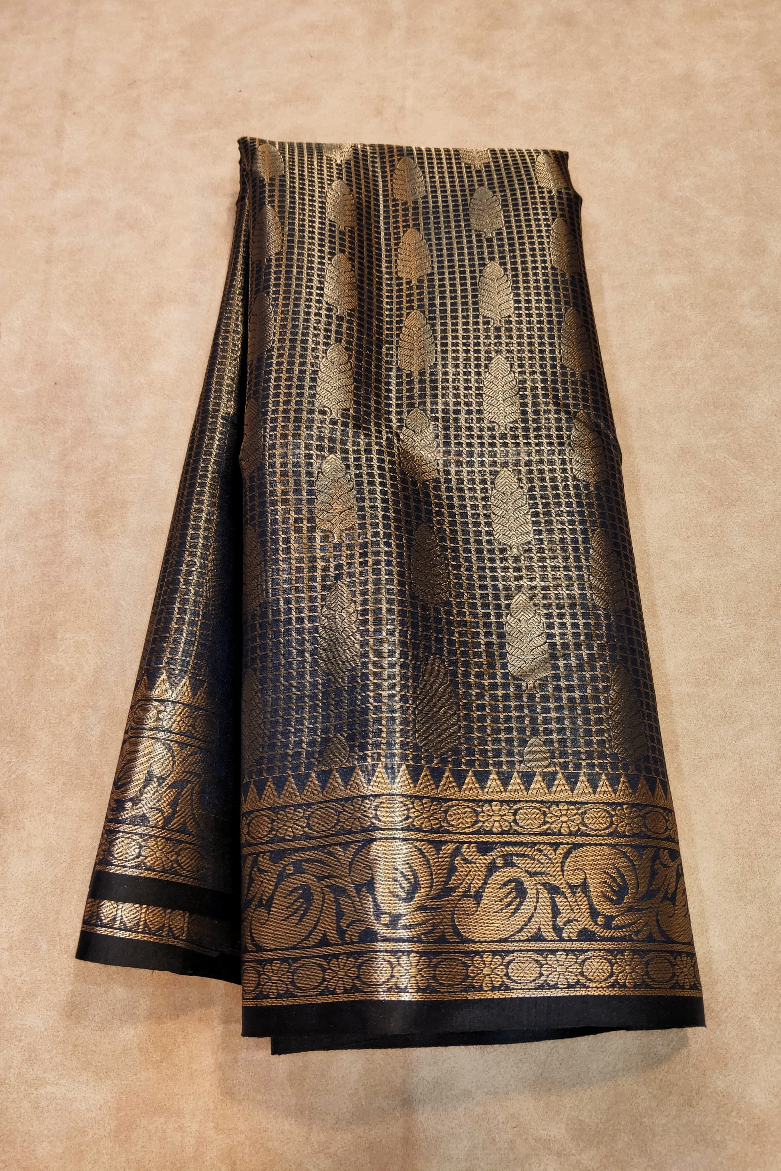 Black and gold patterned fabric on a beige background