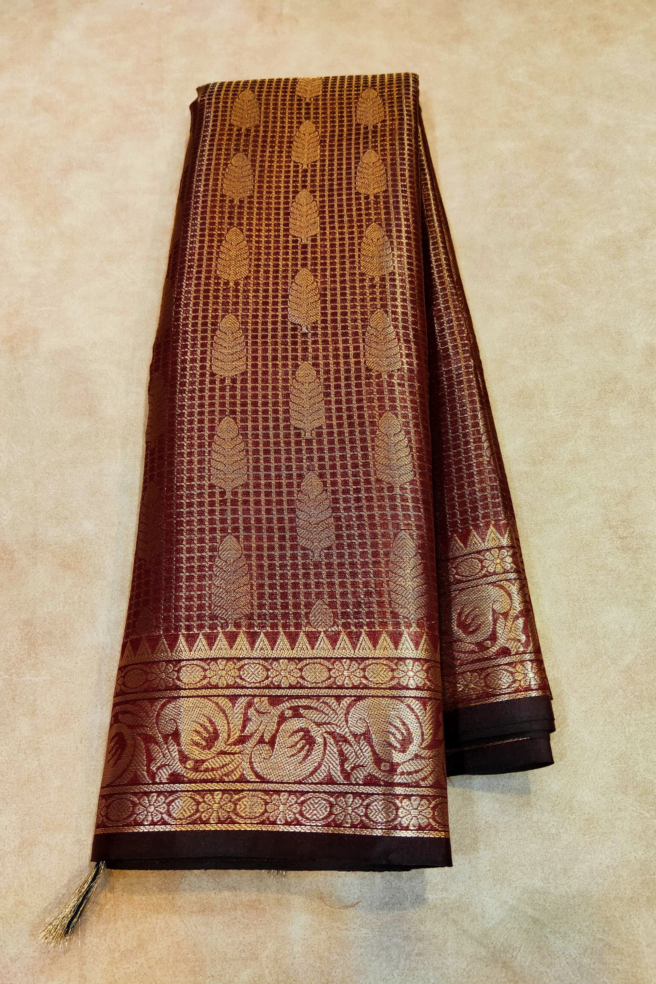 Brown saree with gold patterns on a beige background
