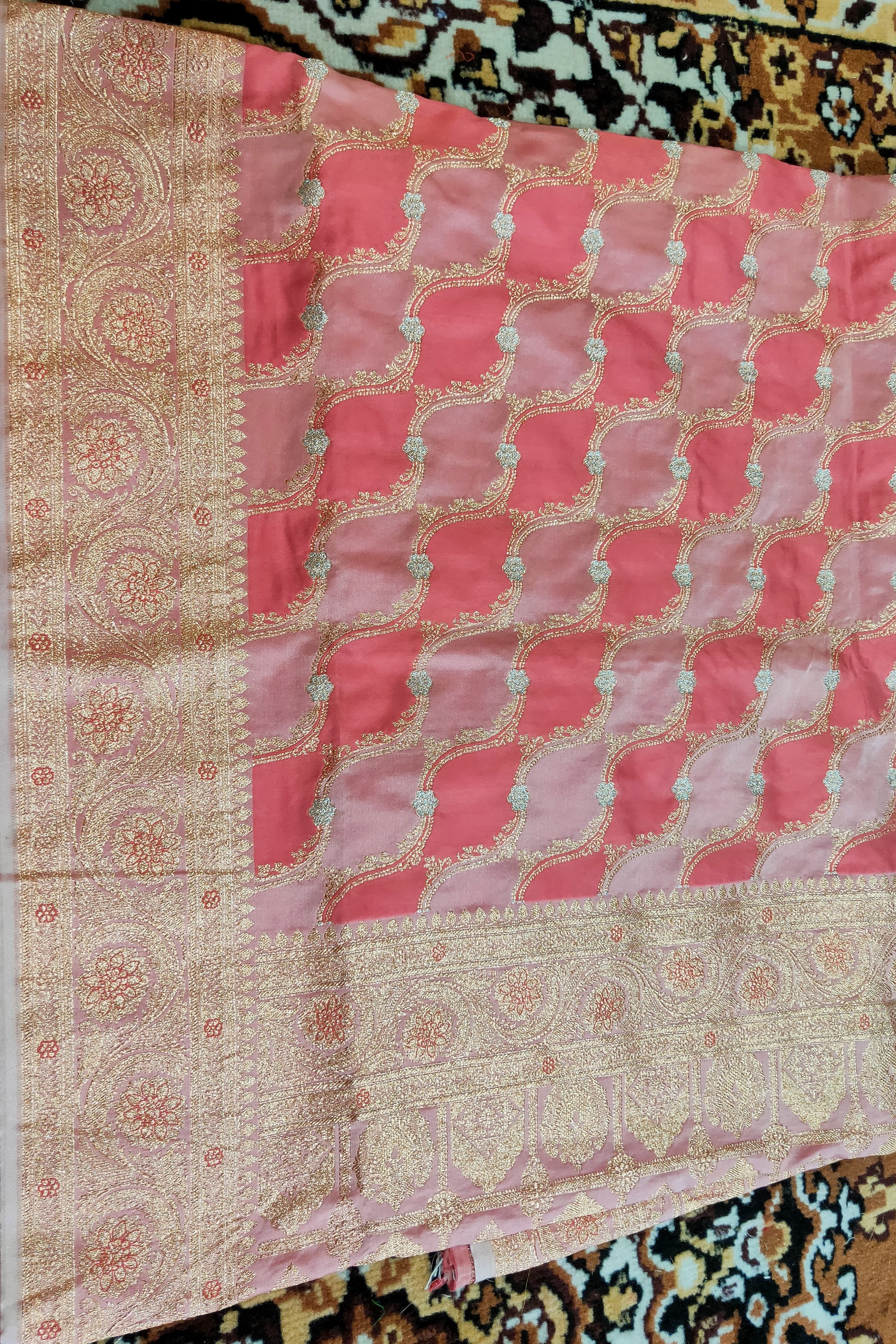 Decorative pink and beige fabric with intricate patterns on a patterned background
