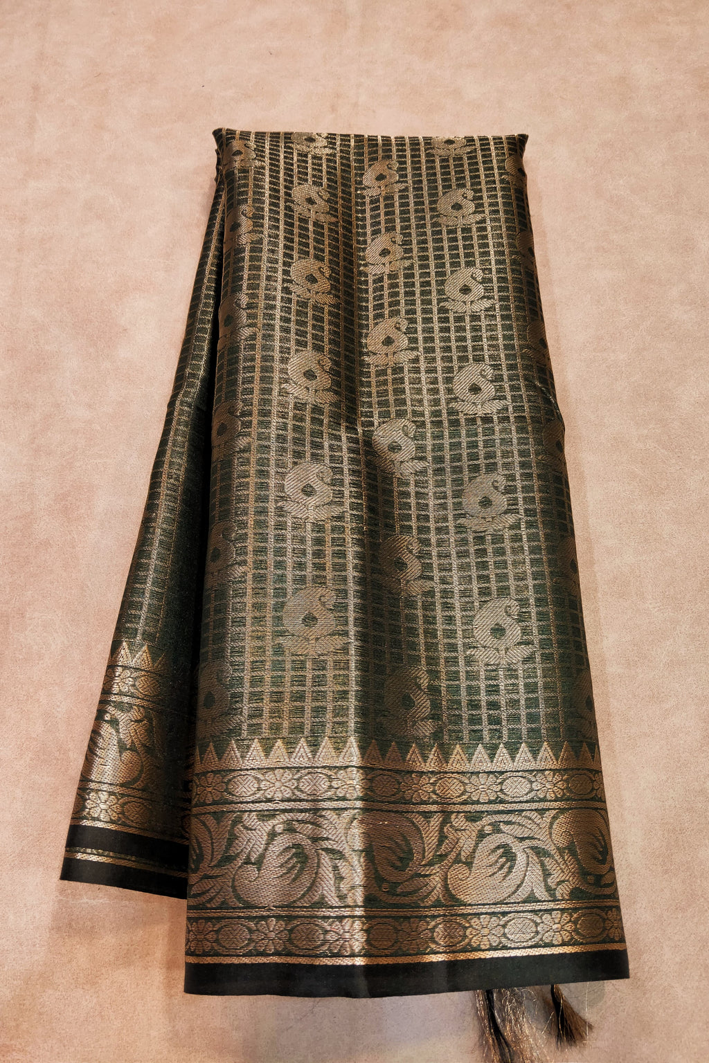 Traditional patterned fabric with black and gold design on a beige background