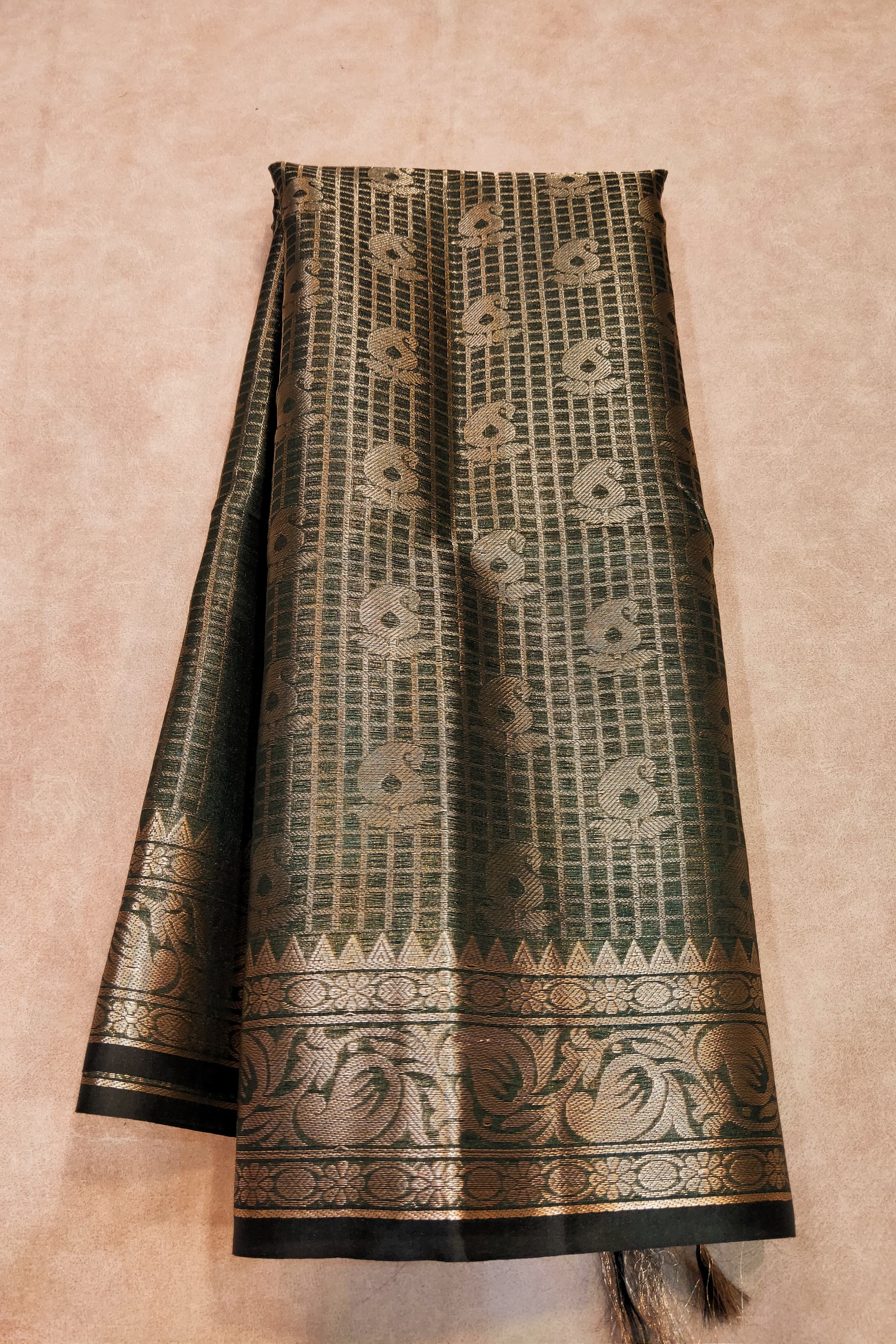 Traditional patterned fabric with black and gold design on a beige background