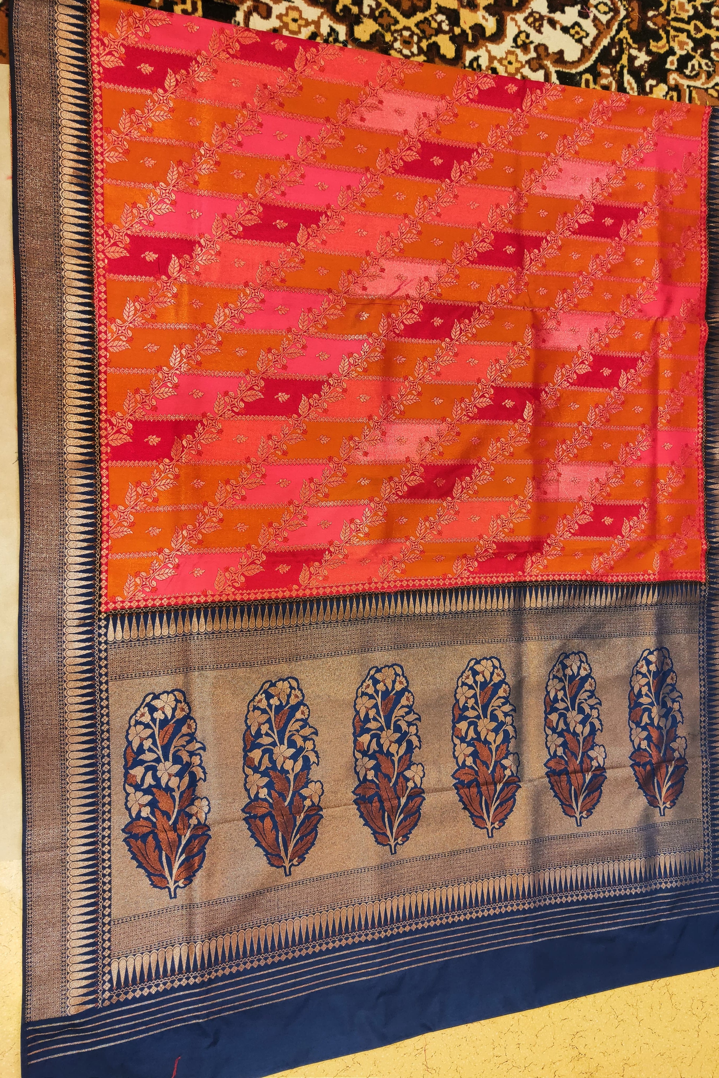 Saree with a red and orange checkered pattern and blue border on a gold background