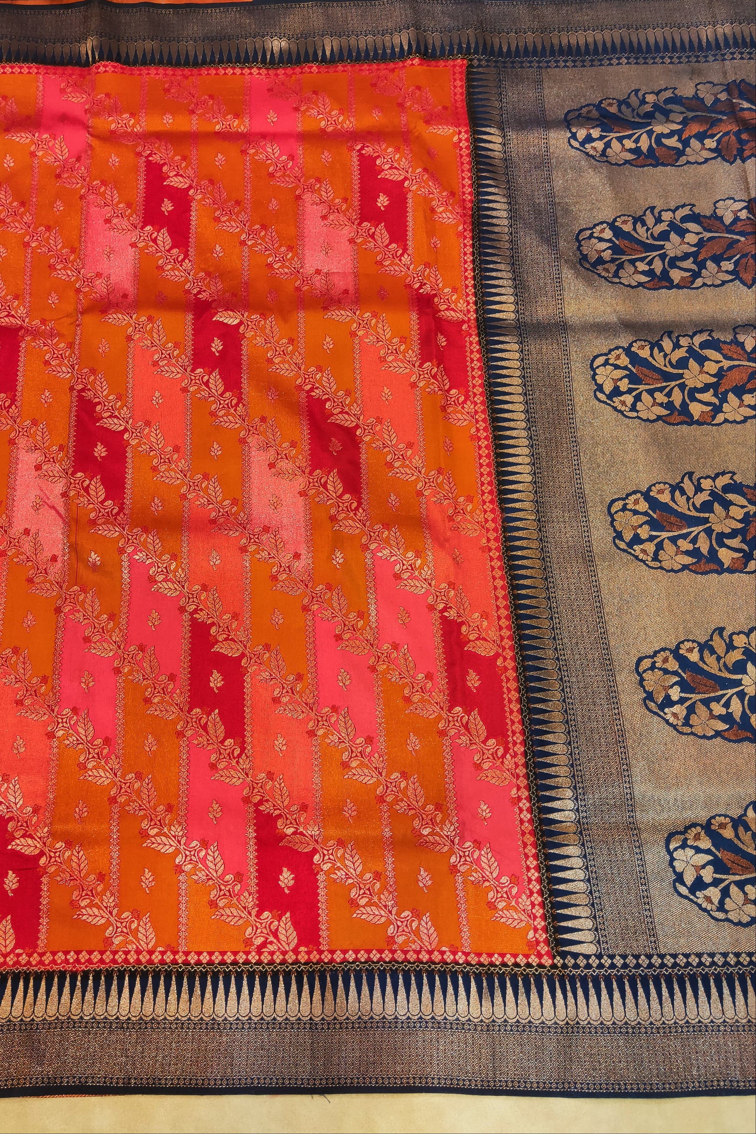 Two patterned cloths, one red and orange with diagonal design, the other blue and beige with paisley patterns, on a wooden surface.