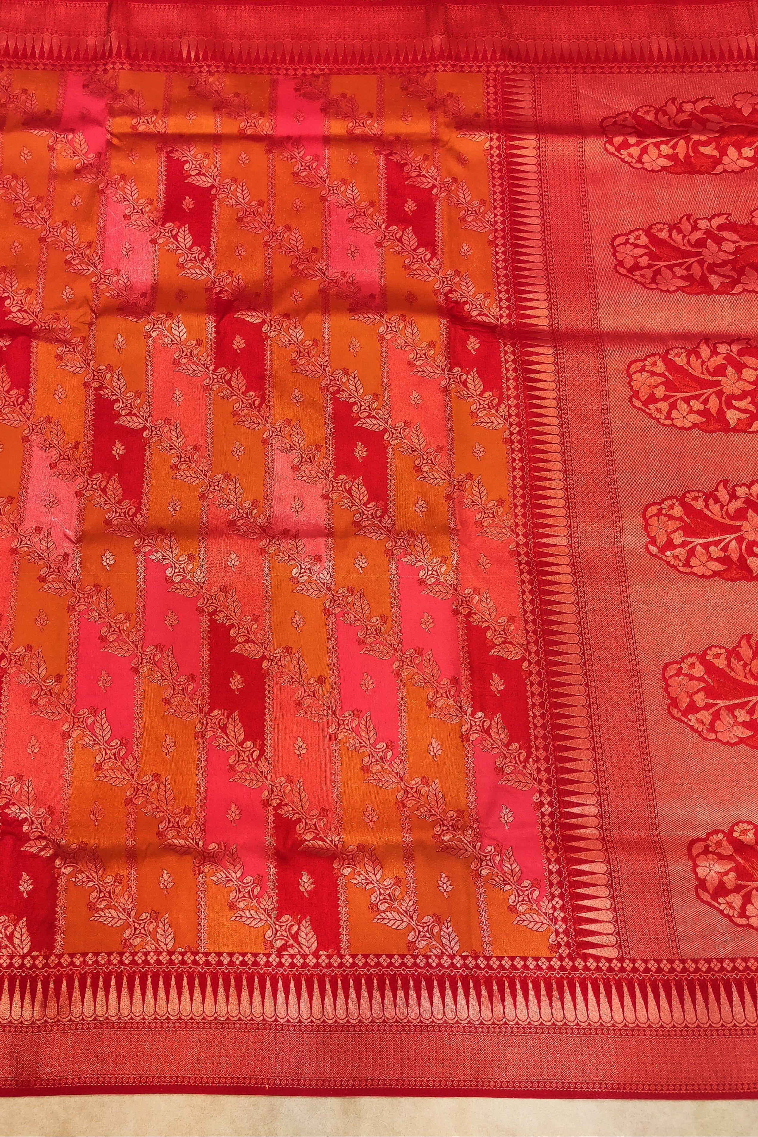 Traditional saree with a red and orange pattern on a plain background