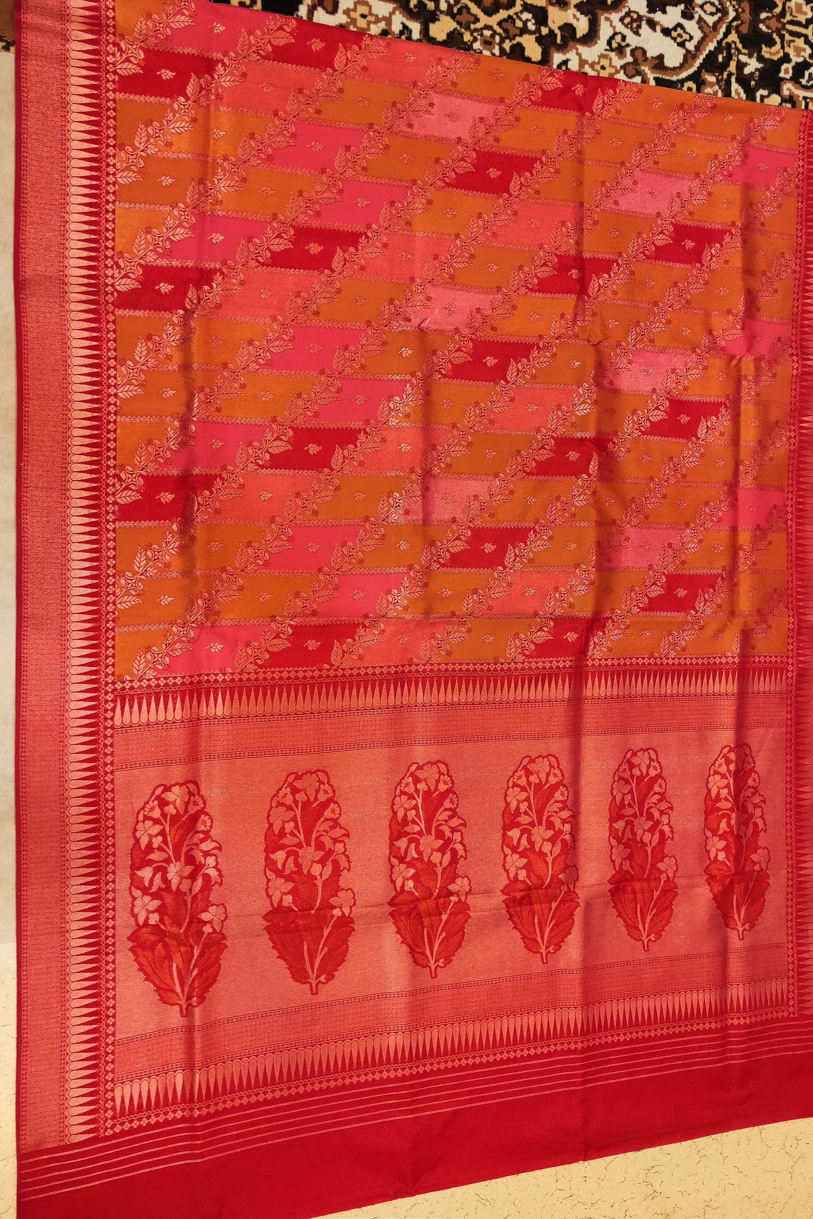 Red and orange saree with a geometric pattern on a plain background
