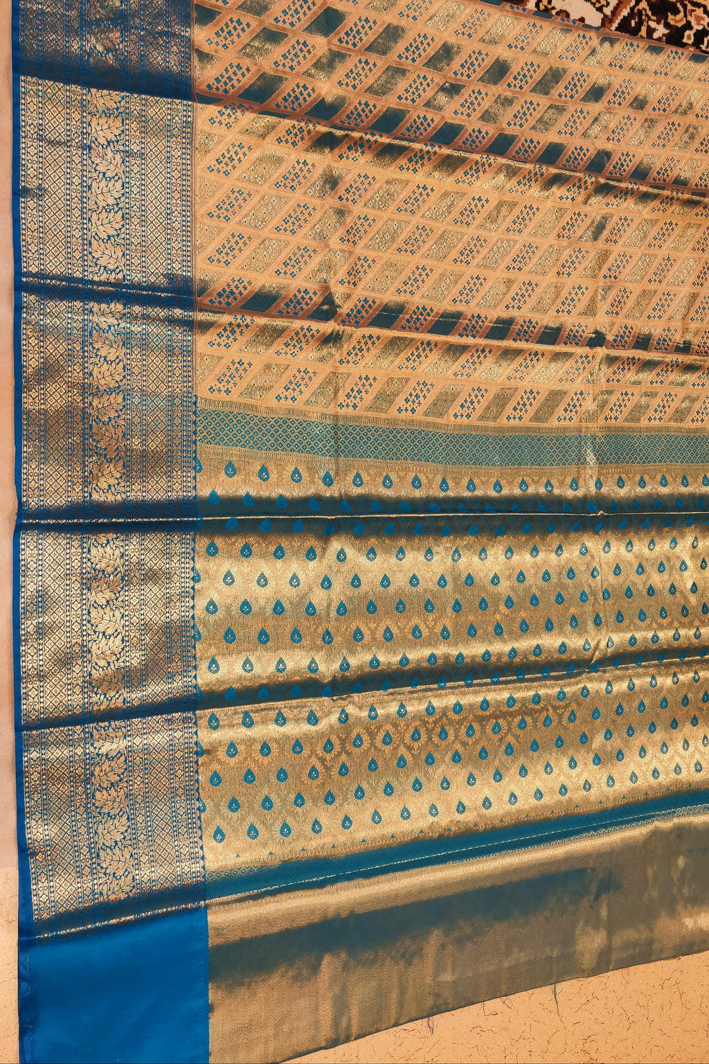 Traditional fabric with blue and gold patterns on a beige background
