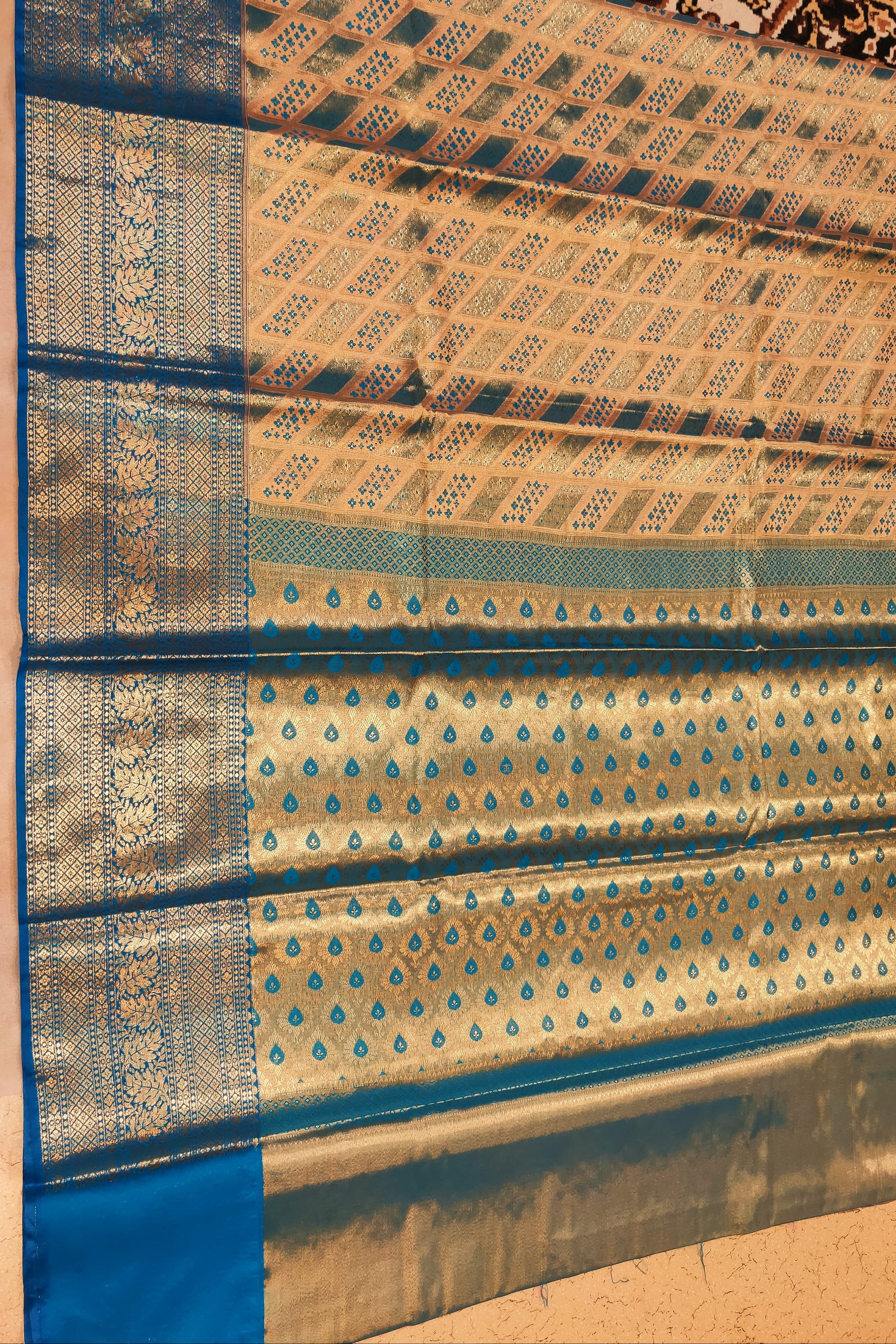 Traditional fabric with blue and gold patterns on a beige background