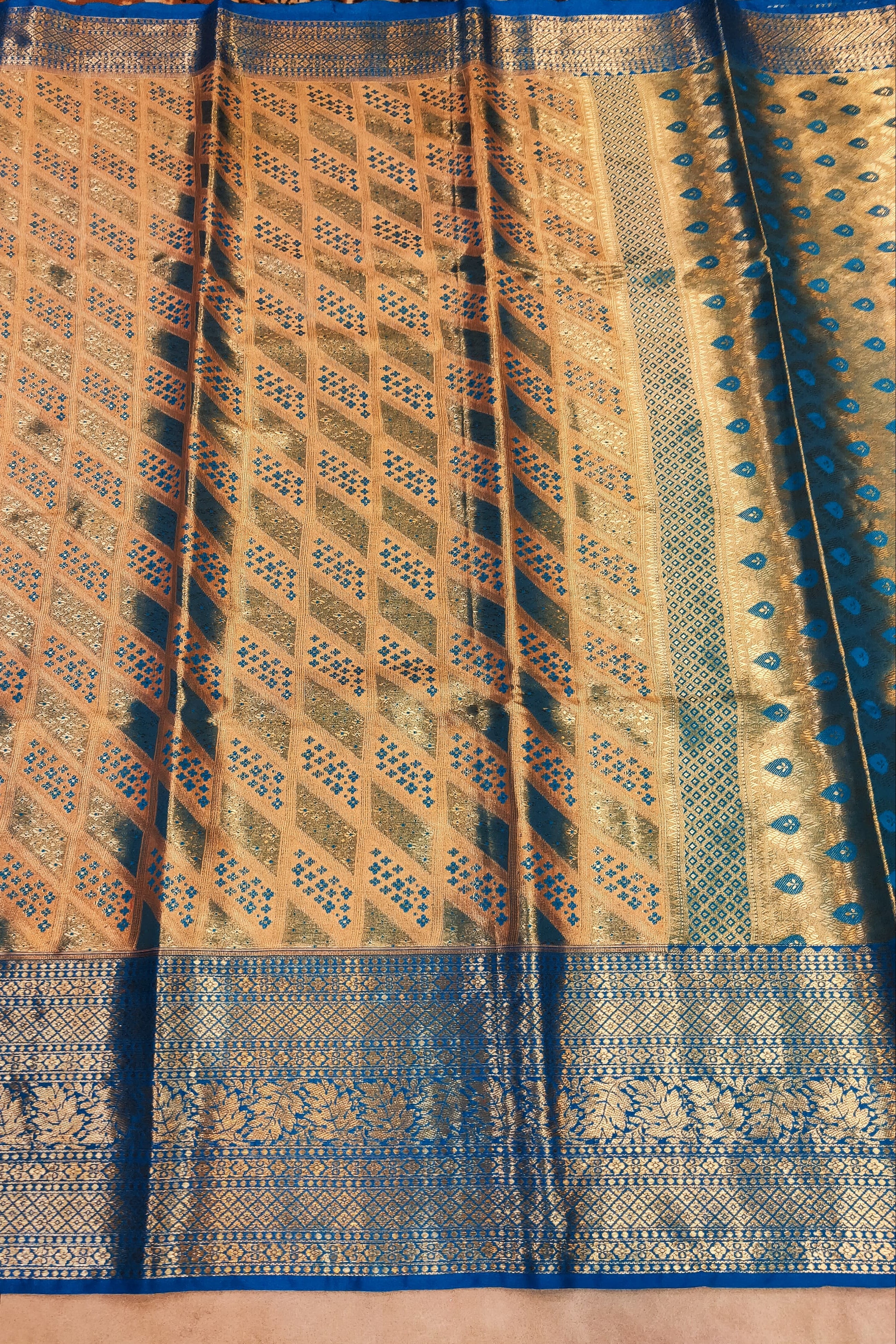 Traditional patterned fabric with blue and gold colors on a textured surface.