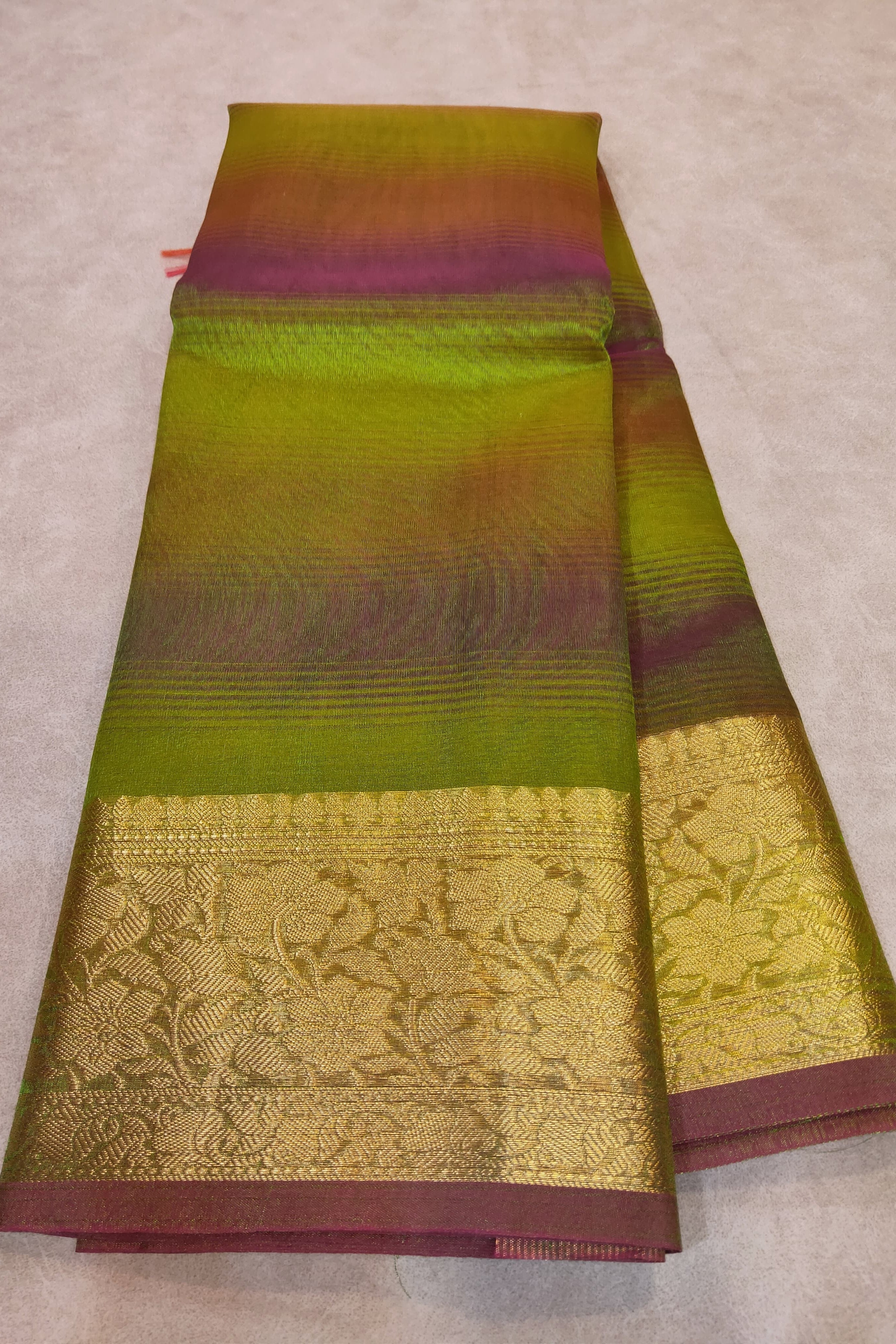 Green and maroon saree with intricate patterns on a beige background