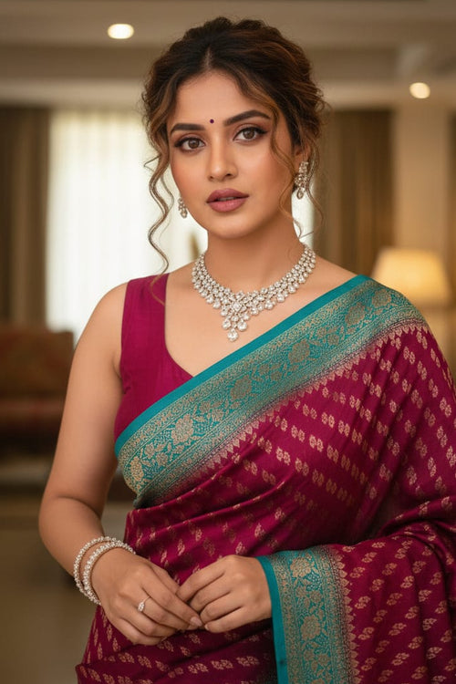 Woman in a traditional maroon saree with a blue border indoors.