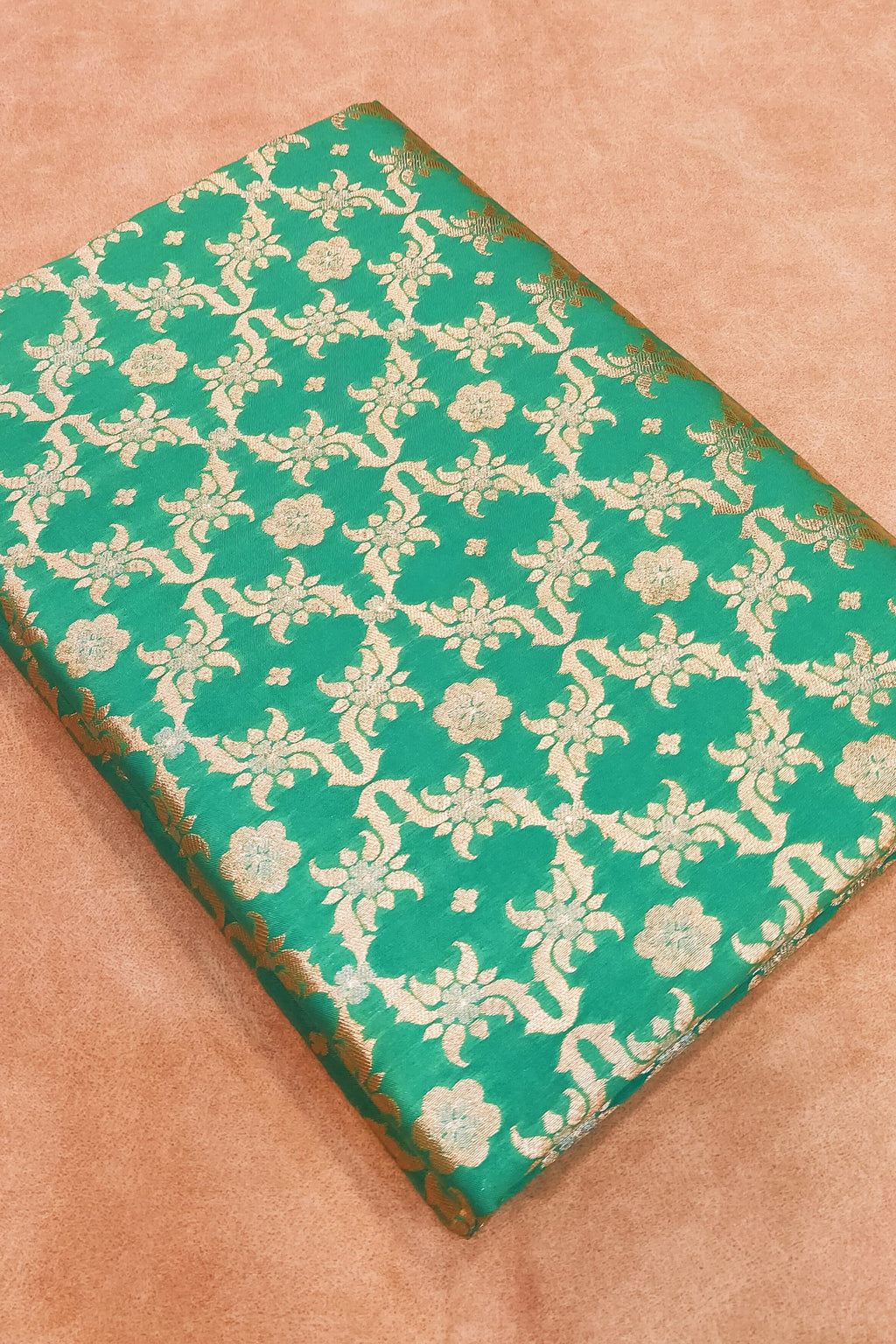 Green fabric with white floral pattern on a beige background