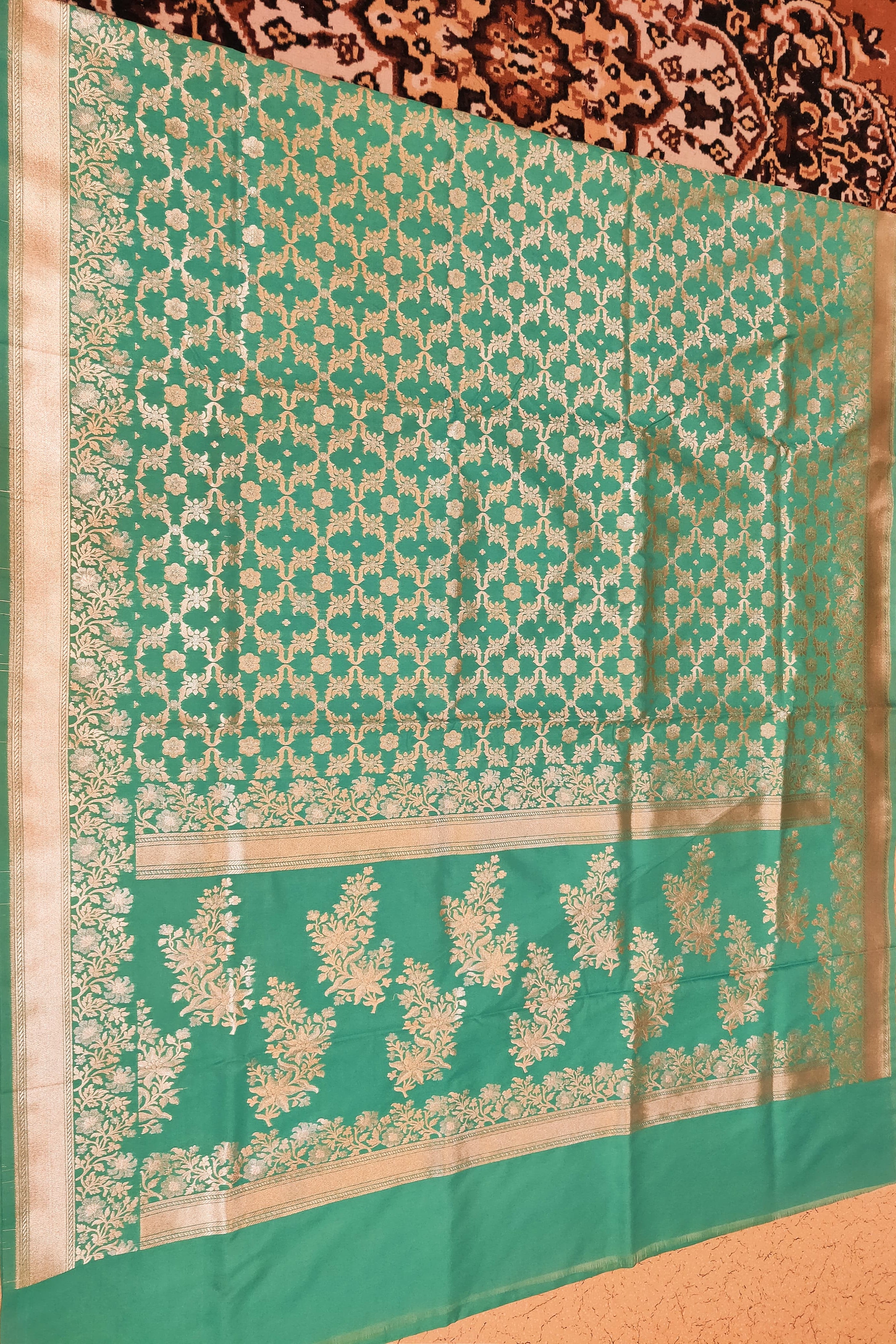Green and beige patterned fabric on a textured surface