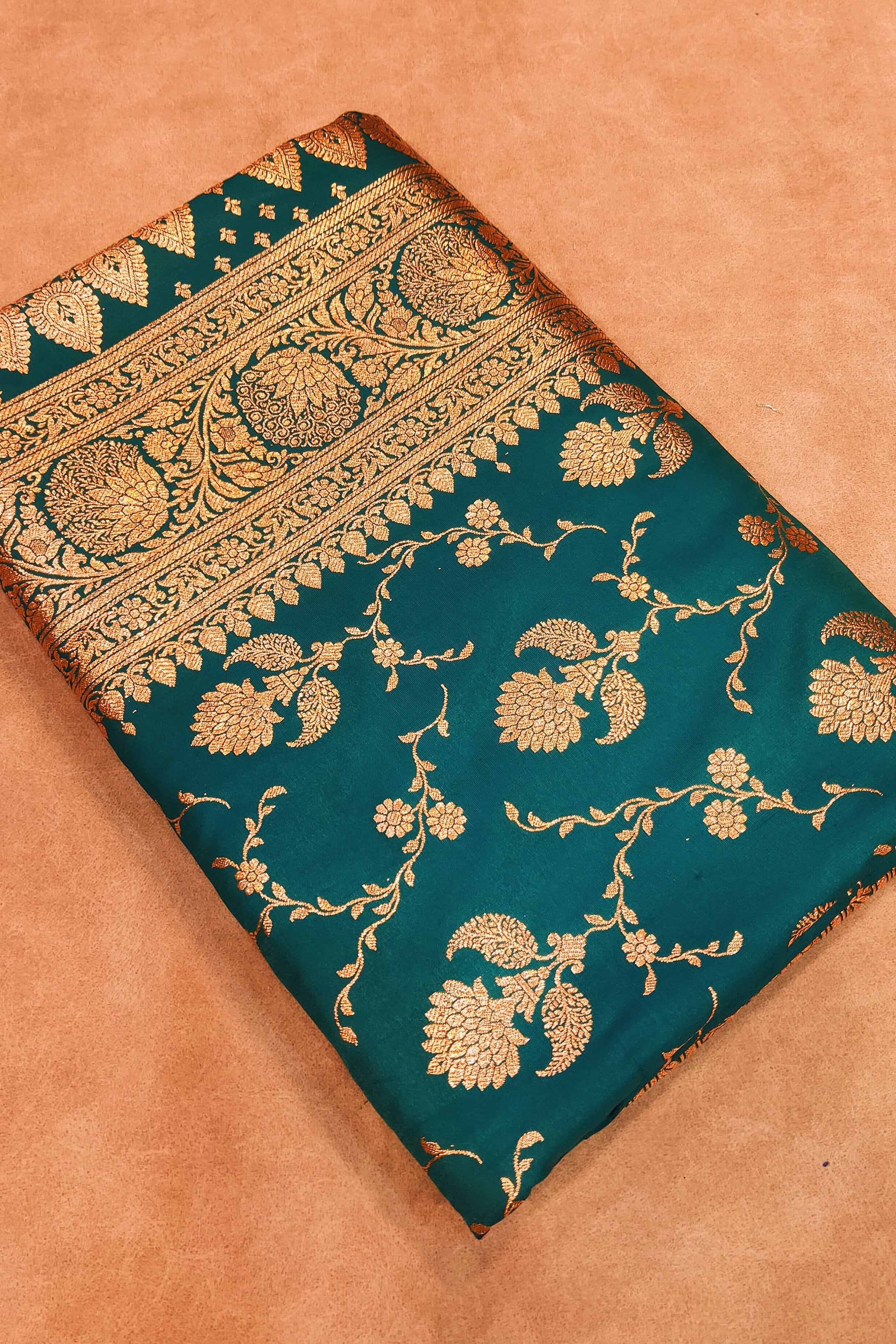 Teal fabric with gold floral patterns on a beige background