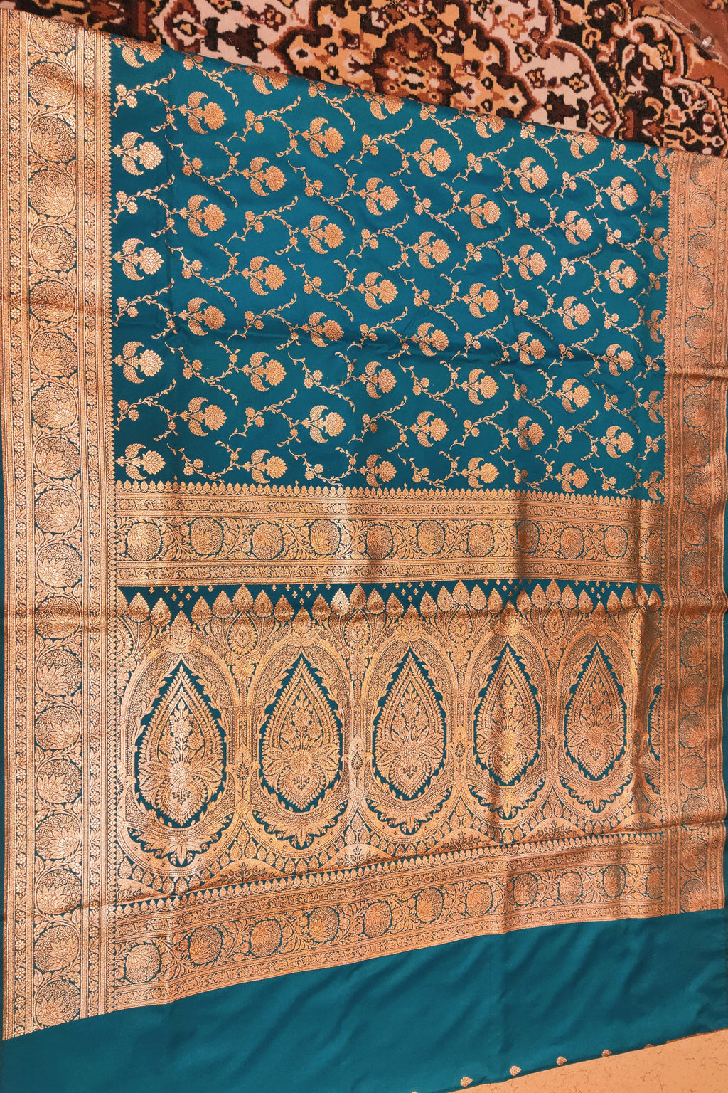Teal and gold patterned fabric on a wooden surface