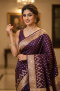 Woman wearing a purple saree with gold patterns indoors