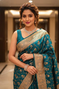 Woman in a blue saree with gold patterns indoors