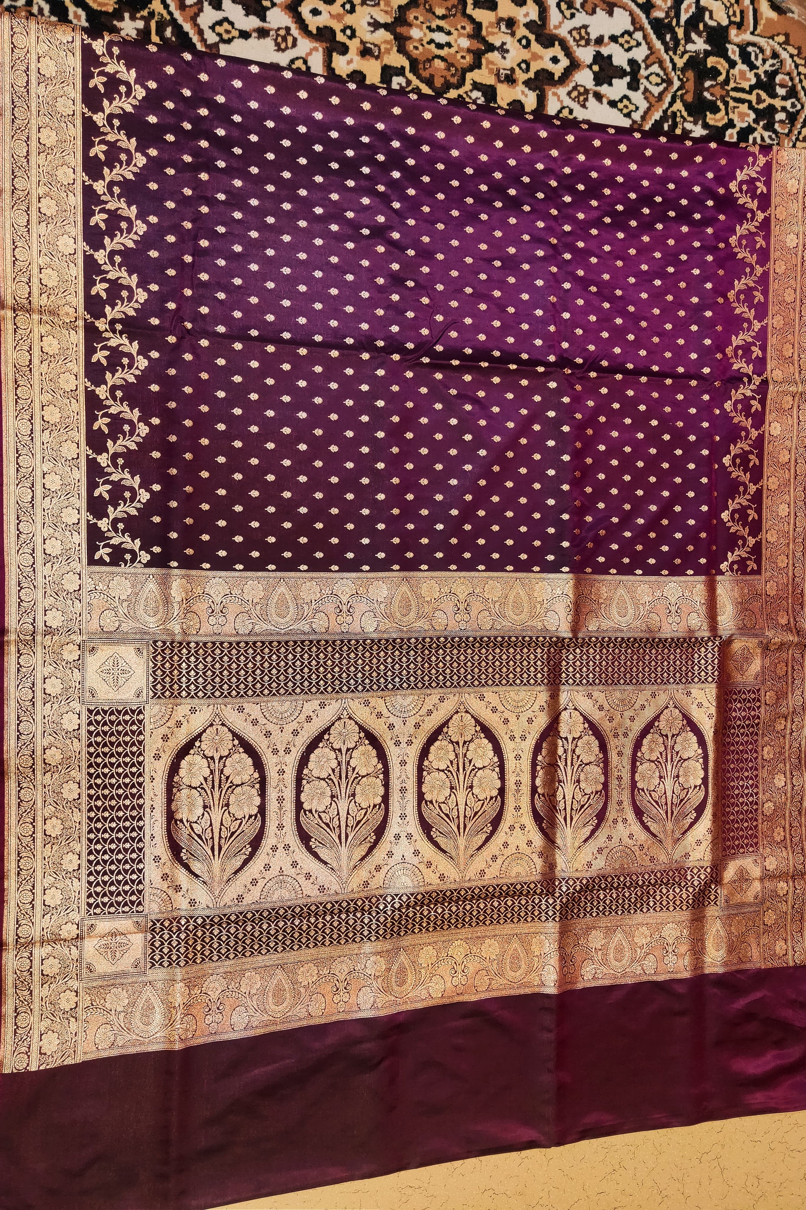 Purple fabric with intricate gold patterns on a textured surface