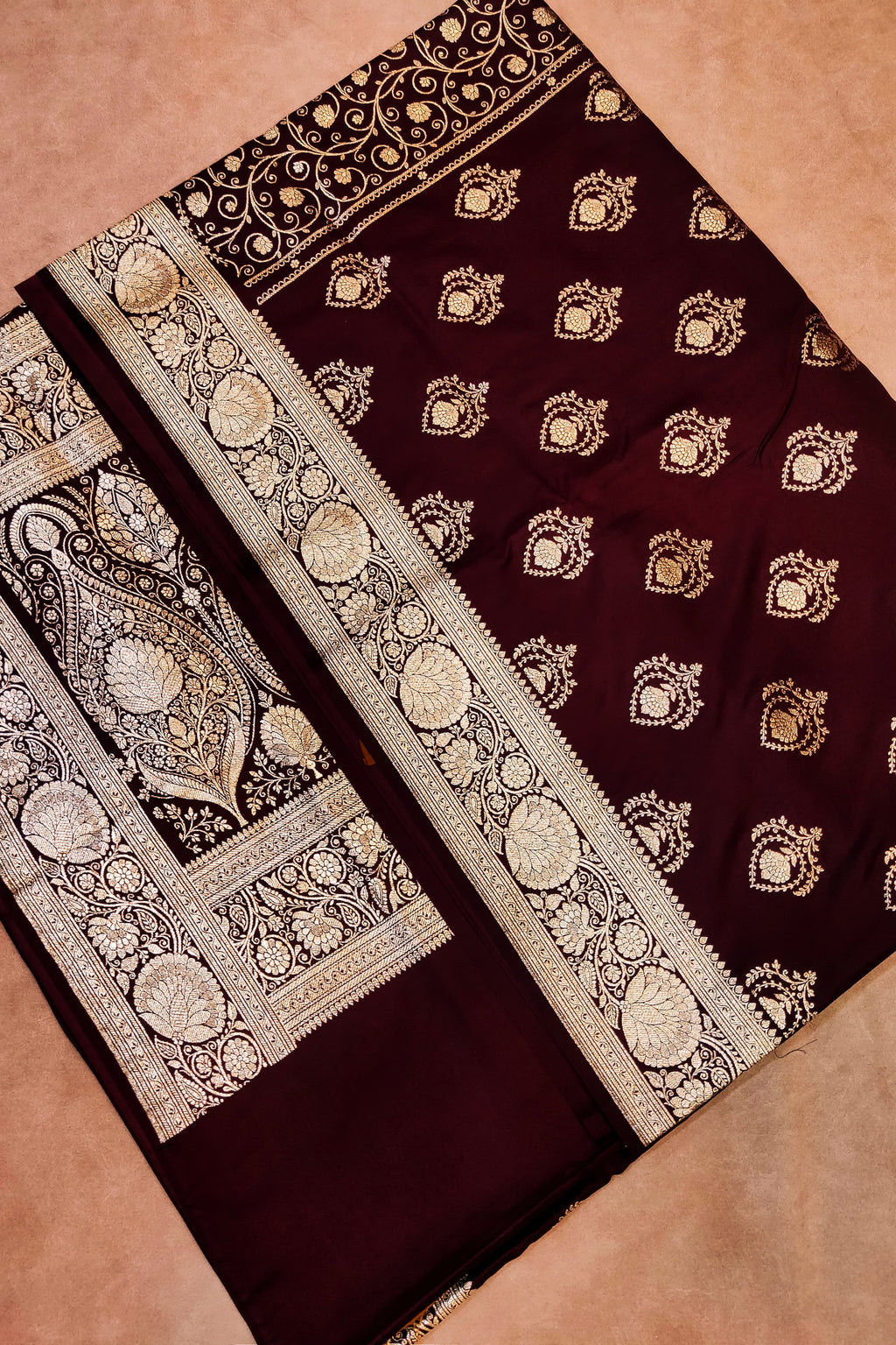 Maroon saree with gold embroidery on a beige background