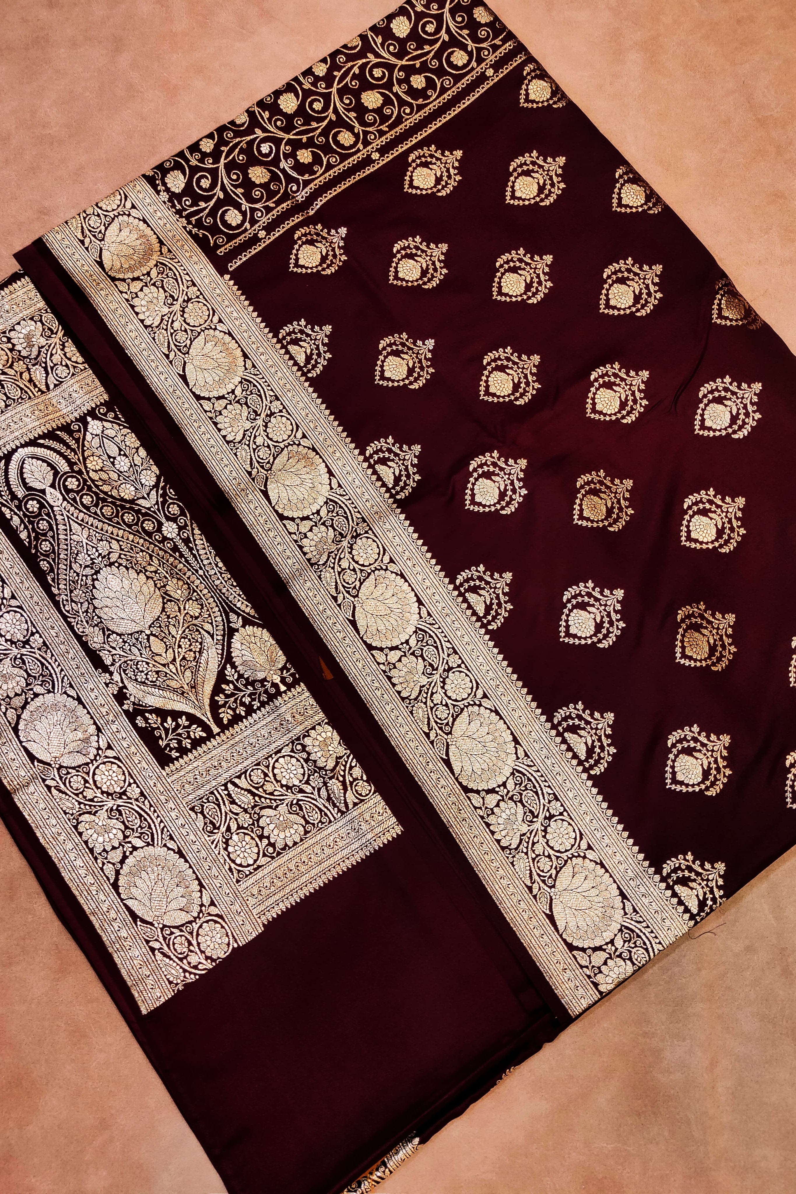 Maroon saree with gold embroidery on a beige background
