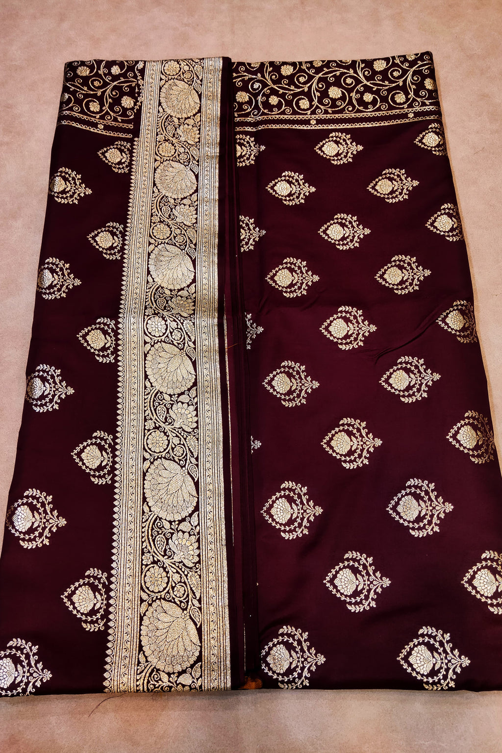 Maroon fabric with white embroidery on a beige background