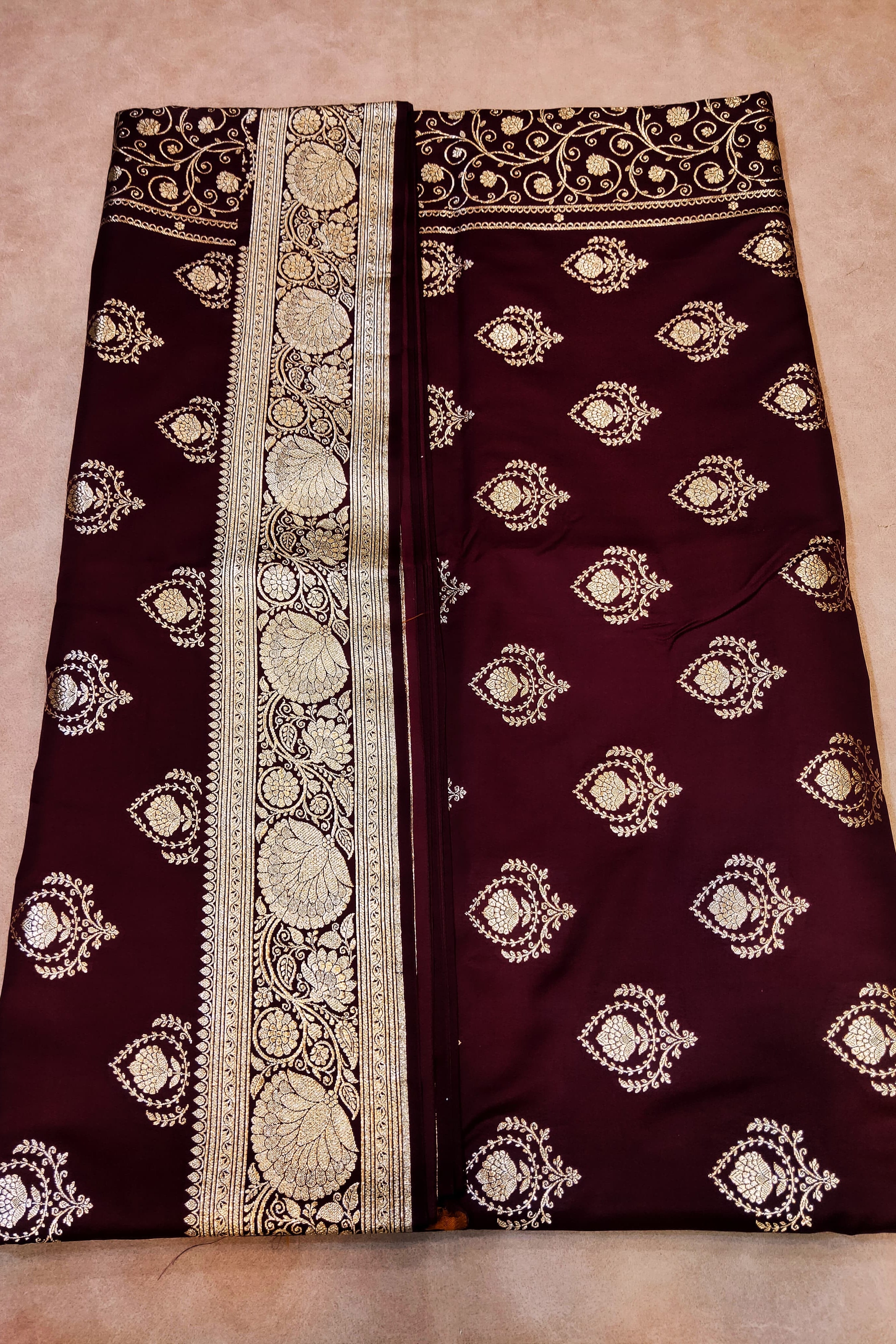 Maroon fabric with white embroidery on a beige background