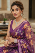 Woman in a purple floral saree with jewelry in an indoor setting