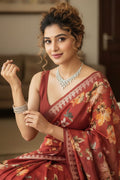 Woman in a red saree with floral patterns indoors