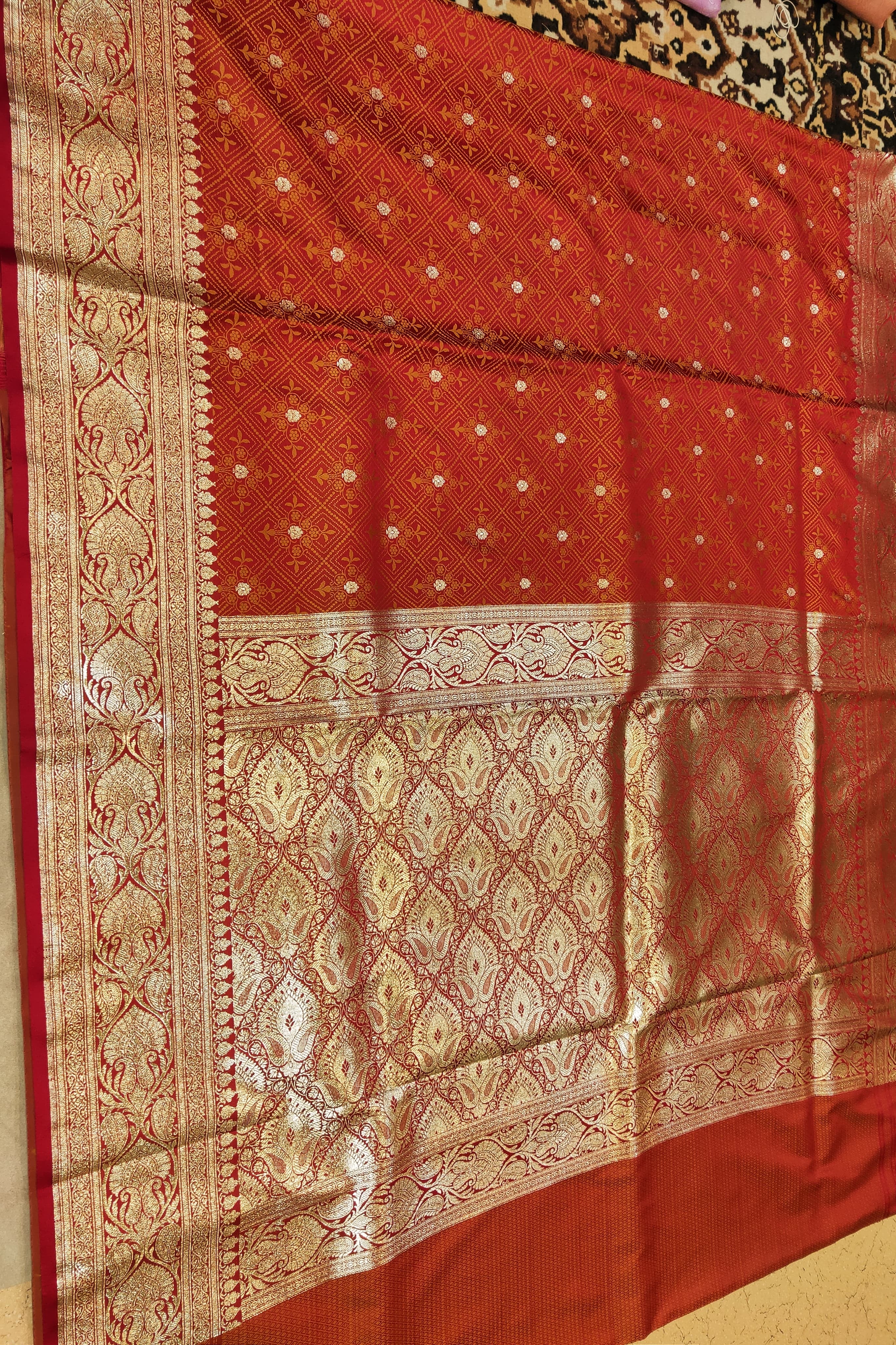 Red and gold patterned fabric on a plain background