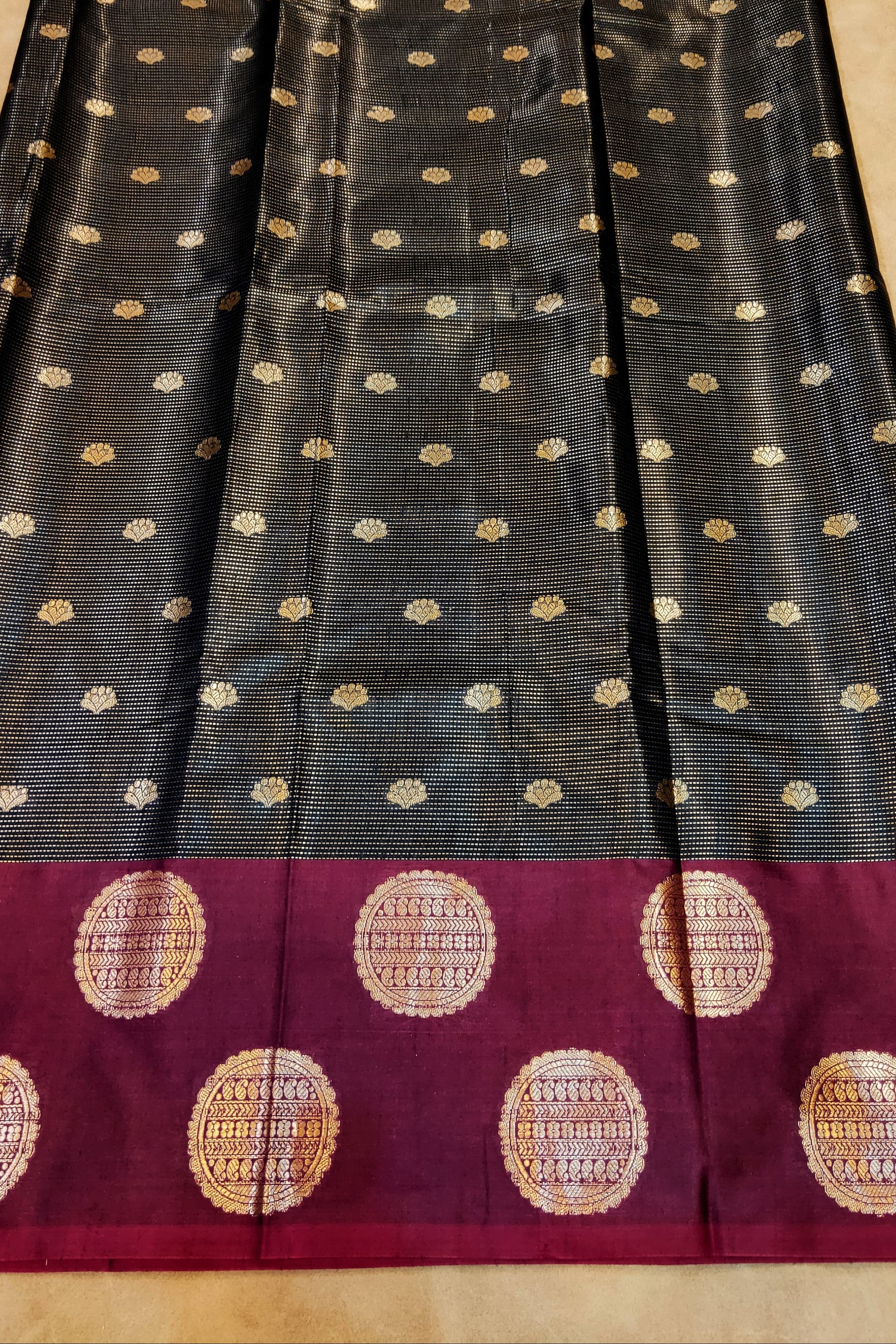 Black saree with gold dot patterns on a beige surface