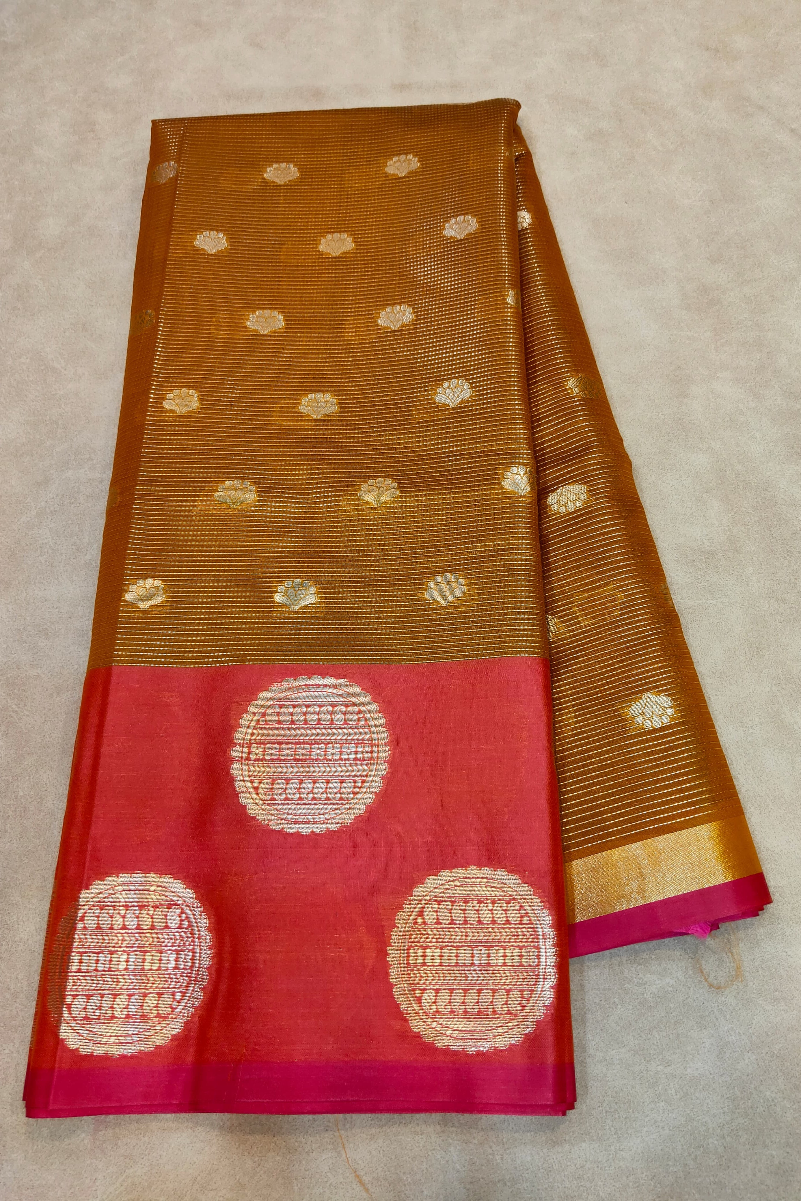 Brown and red saree with gold patterns on a beige background