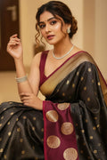 Woman in a traditional saree with gold patterns and jewelry indoors.