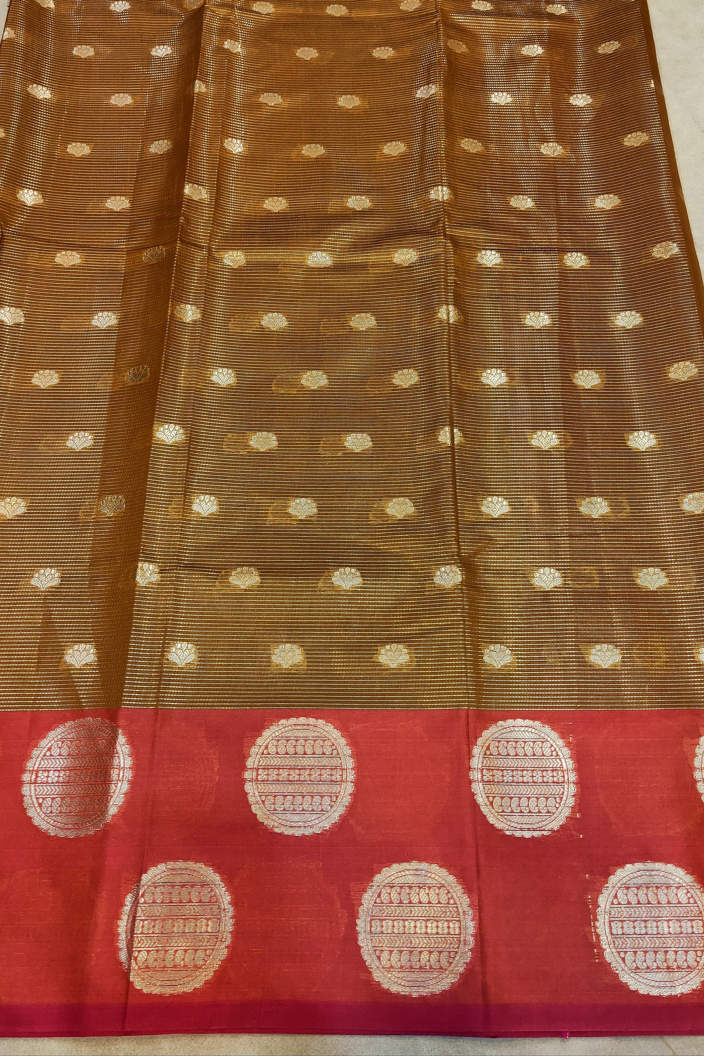 Brown and red saree with white dot patterns on a plain background
