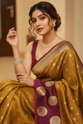 Woman wearing a traditional maroon and gold saree with jewelry indoors.