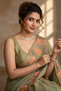 Woman in a green saree with floral patterns indoors