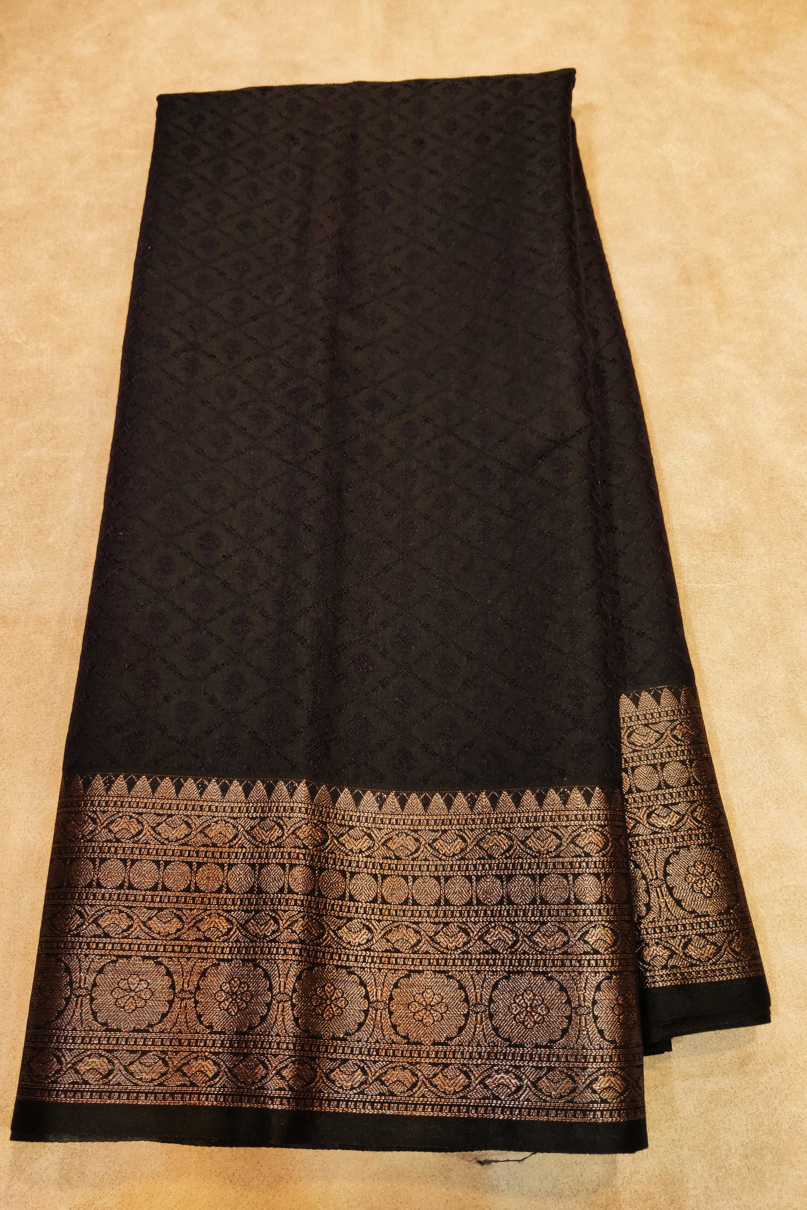 Black fabric with intricate patterns on a beige background