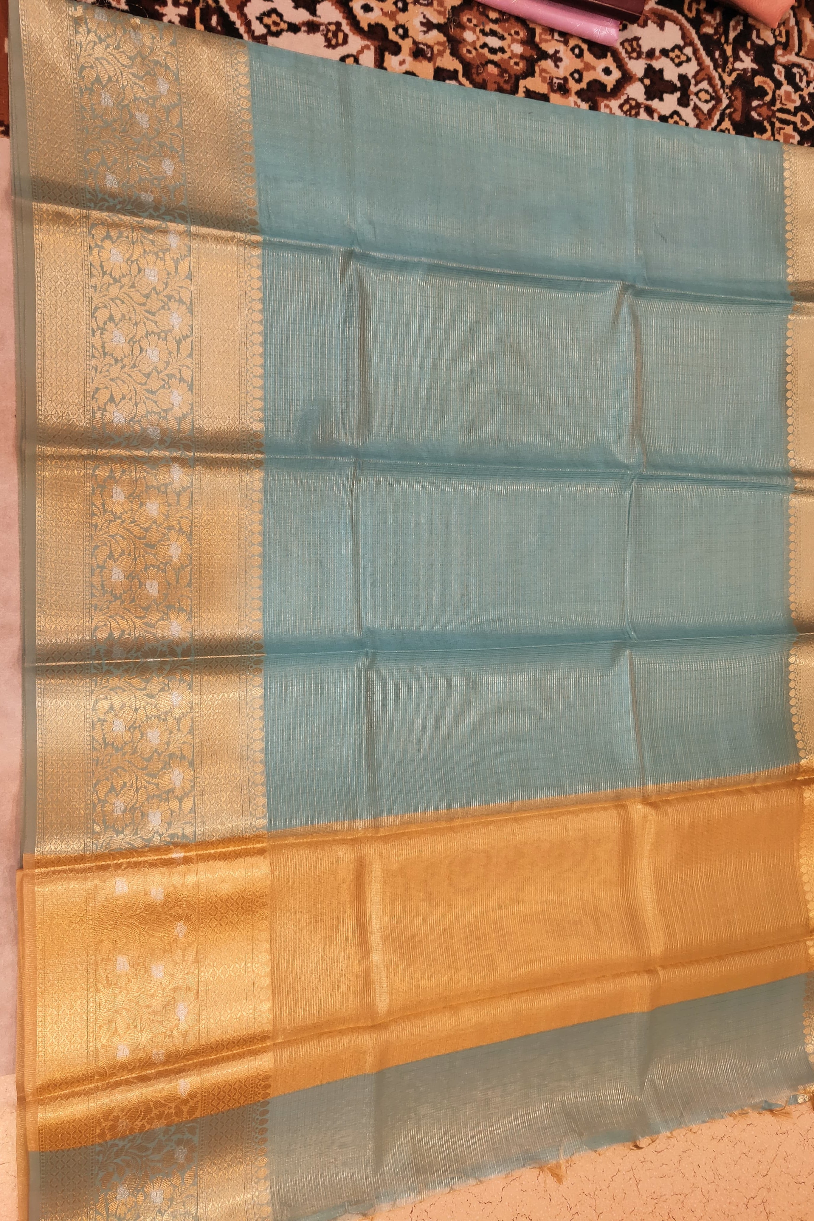 Traditional saree with a blue and gold border on a patterned fabric background