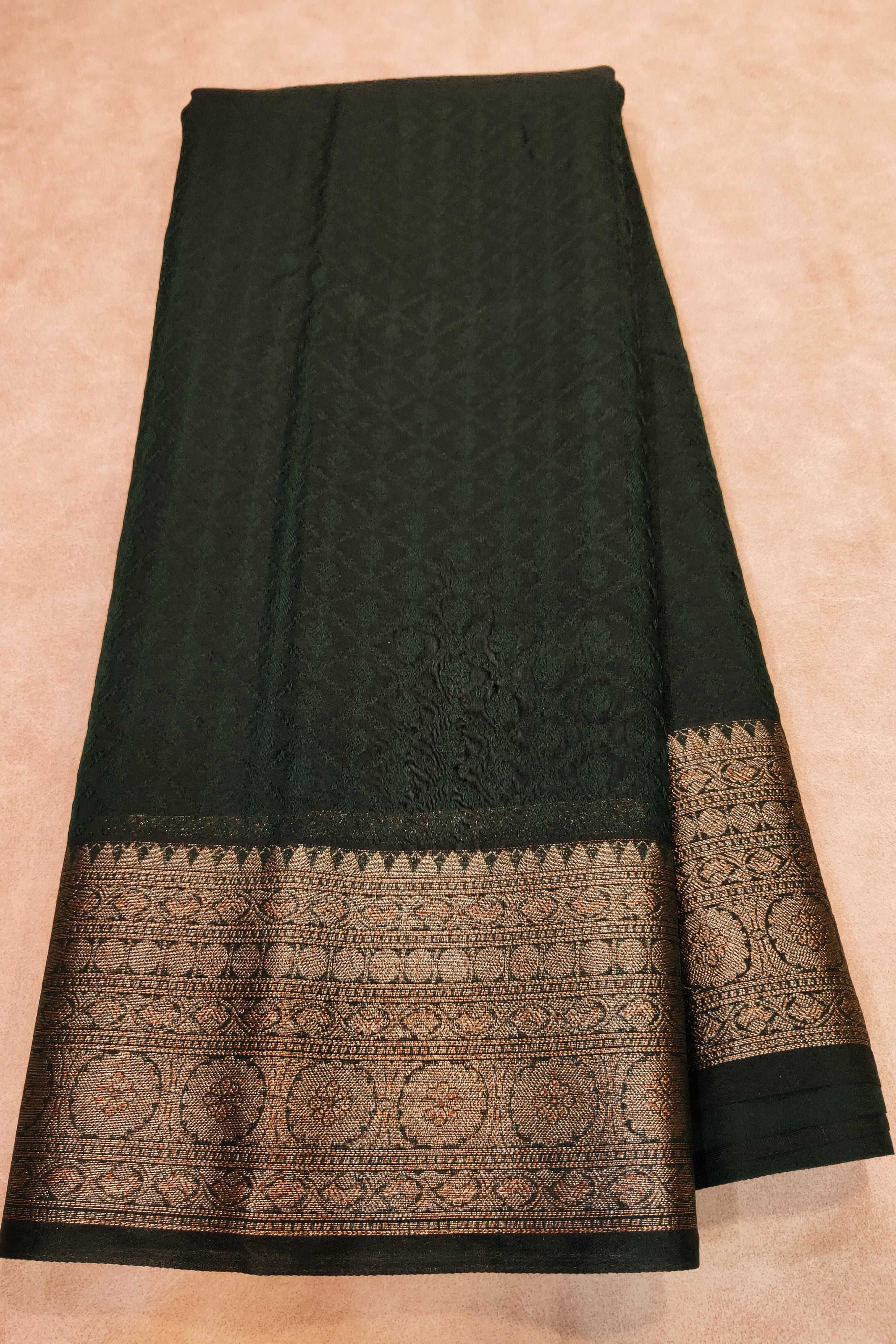 Black saree with intricate gold patterns on a beige background