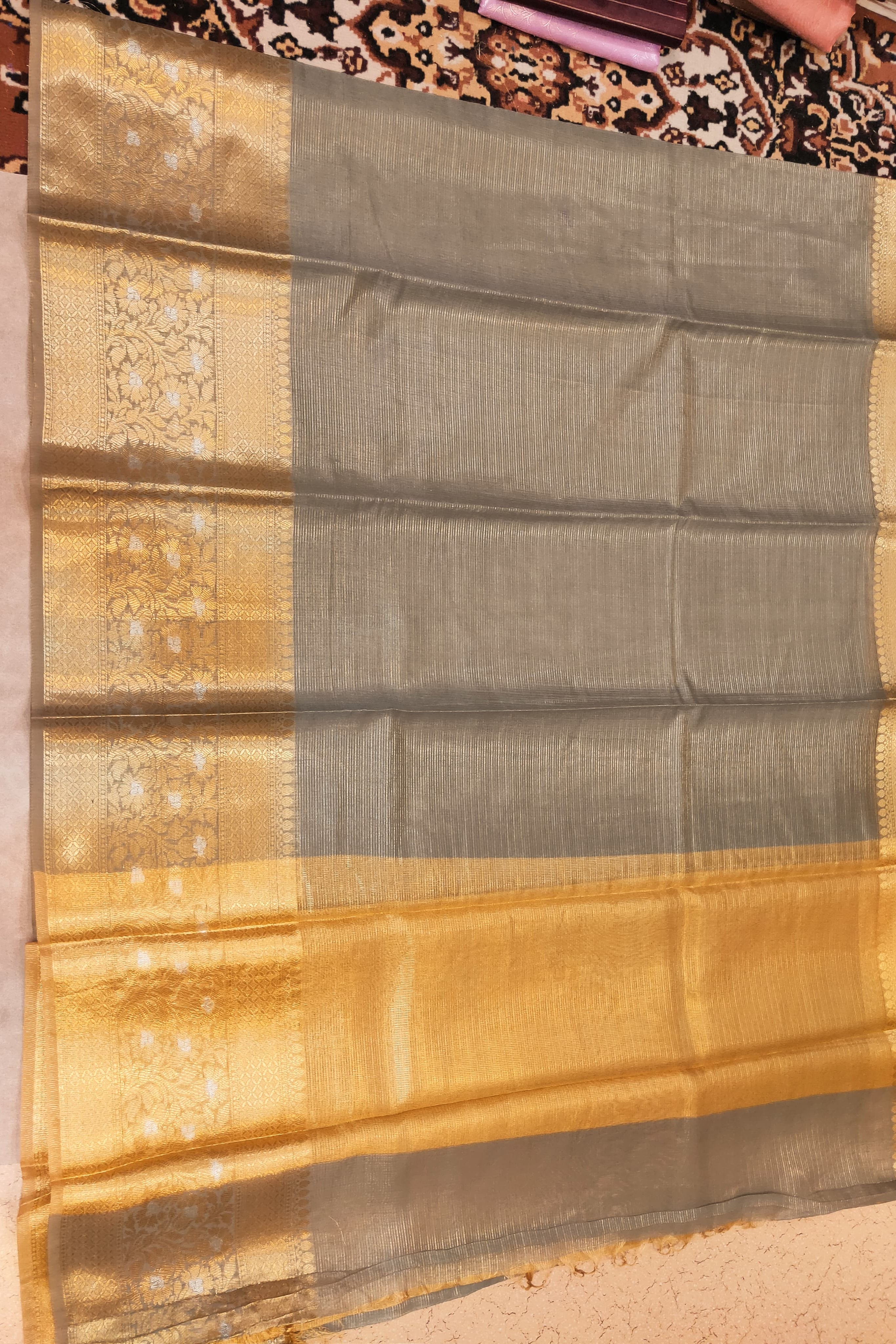 Traditional saree with gold and gray pattern on a fabric background