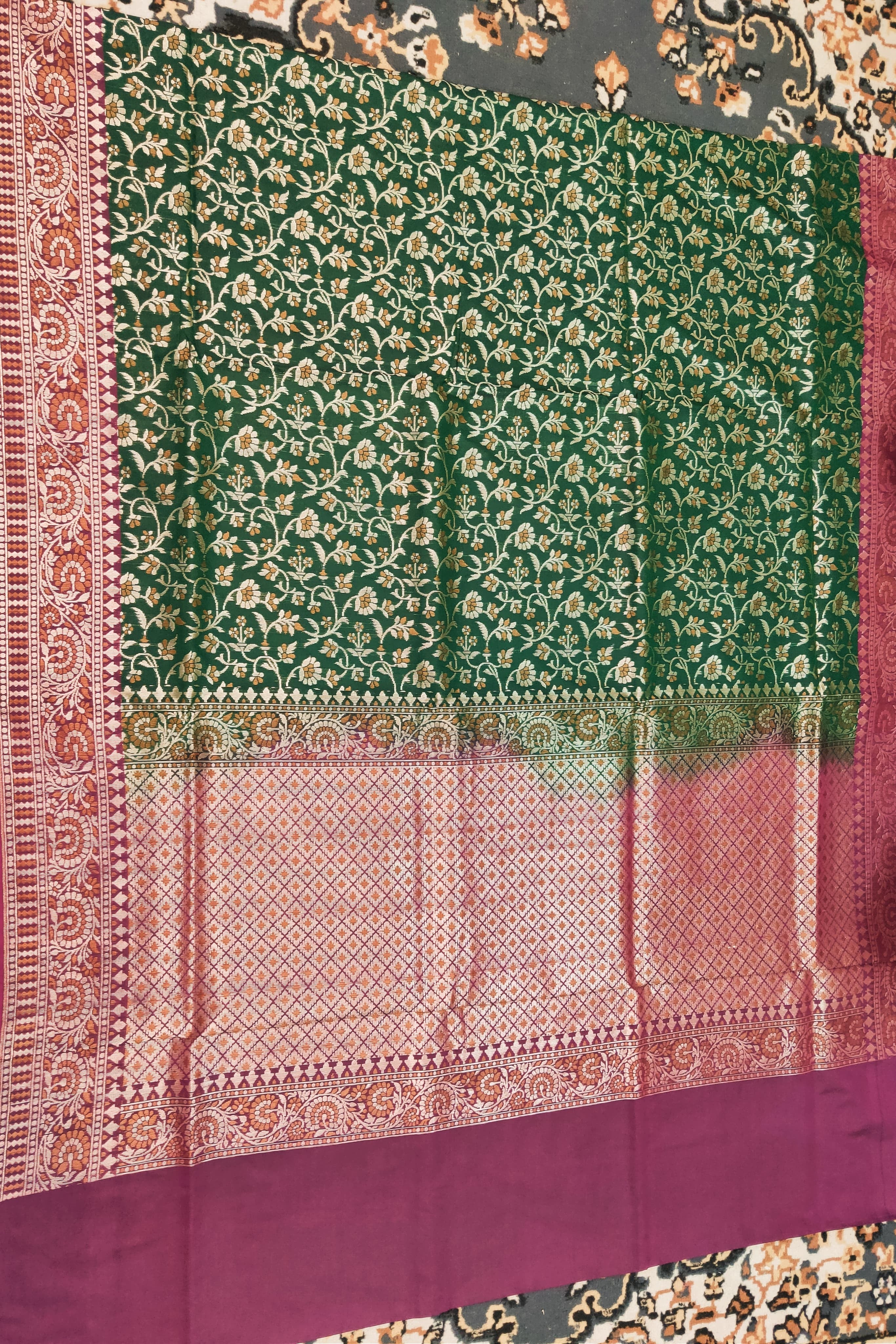 Green and purple traditional fabric with intricate patterns on a patterned background