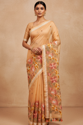 Woman wearing a beige saree with floral patterns on a beige background