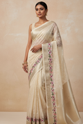 Woman wearing a beige saree with floral patterns on a beige background